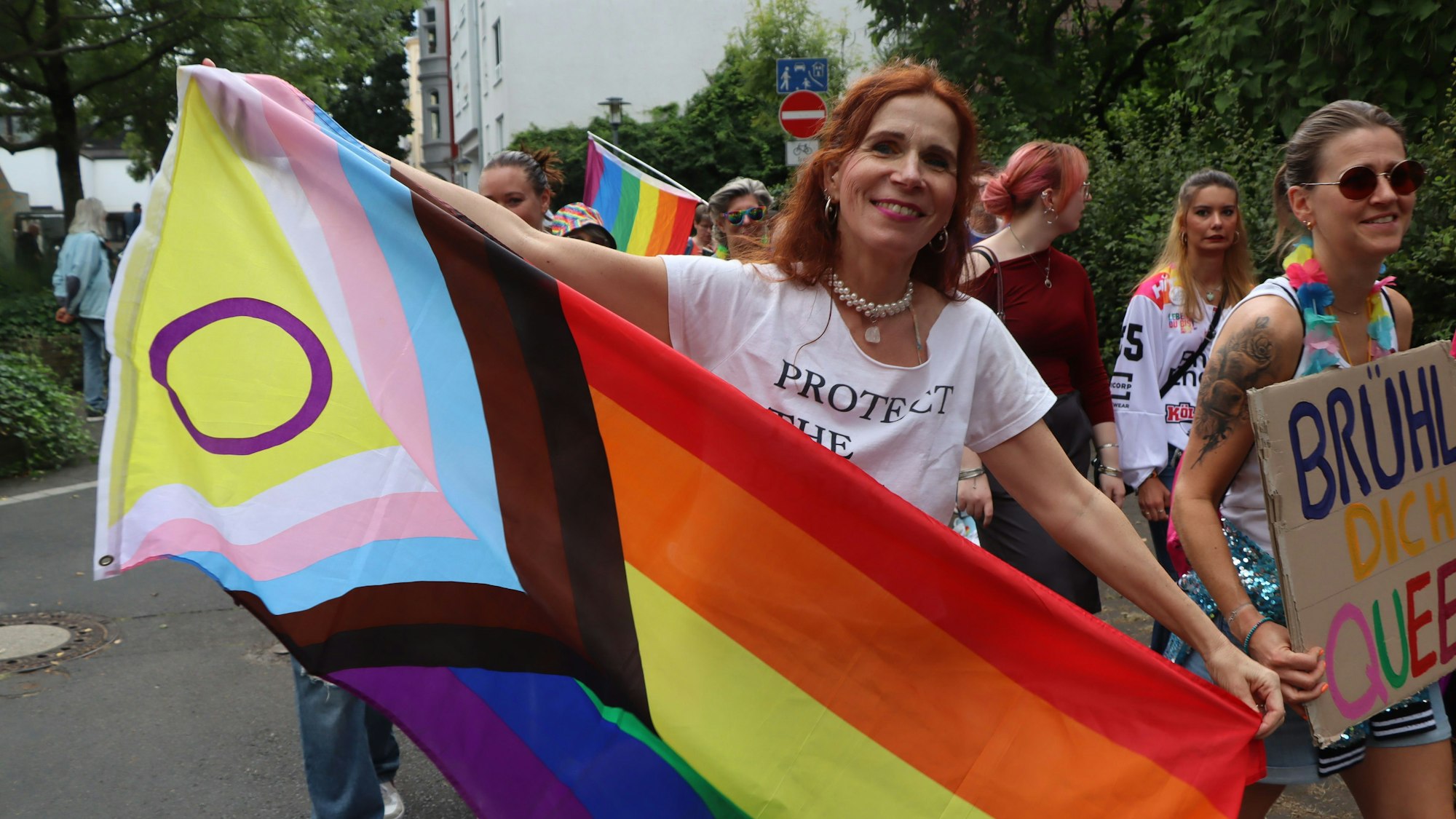 Zu sehen ist eine Frau, die eine Regebogenfahne in den Händen hält.
