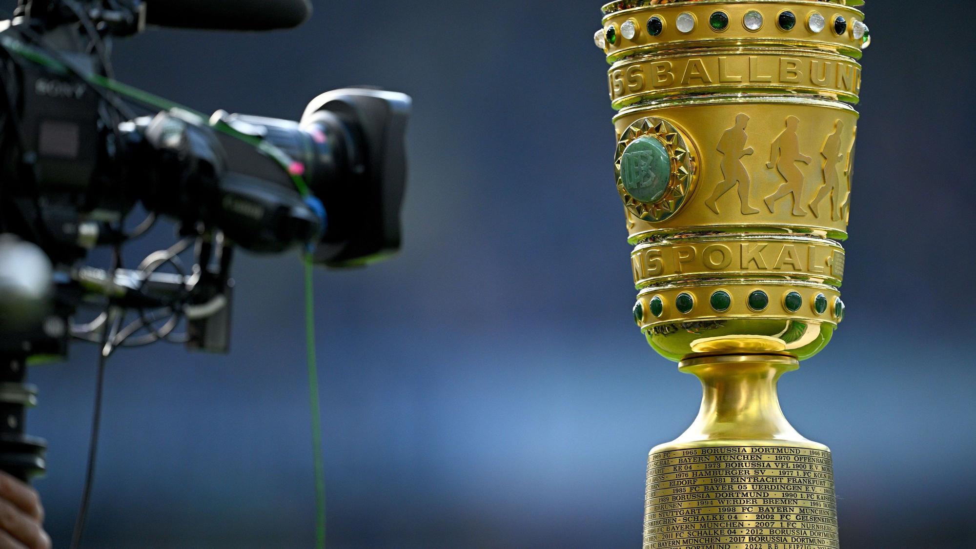 Eine Kamera vor der Siegestrophäe. (zu dpa: «Bayern im Pokal nach Köln - Top-Duell Frankfurt gegen BVB») Foto: Tom Weller/dpa +++ dpa-Bildfunk +++