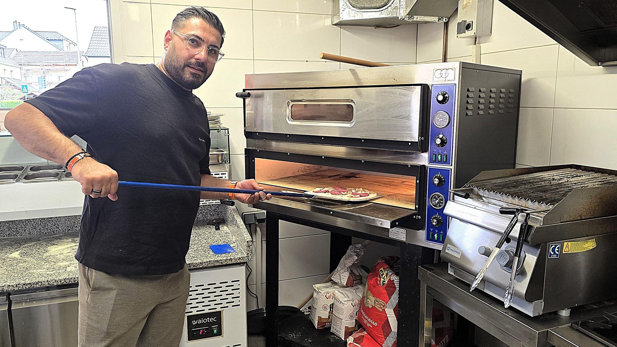 Aziogla Abdulla schiebt die Pizza in den Ofen.