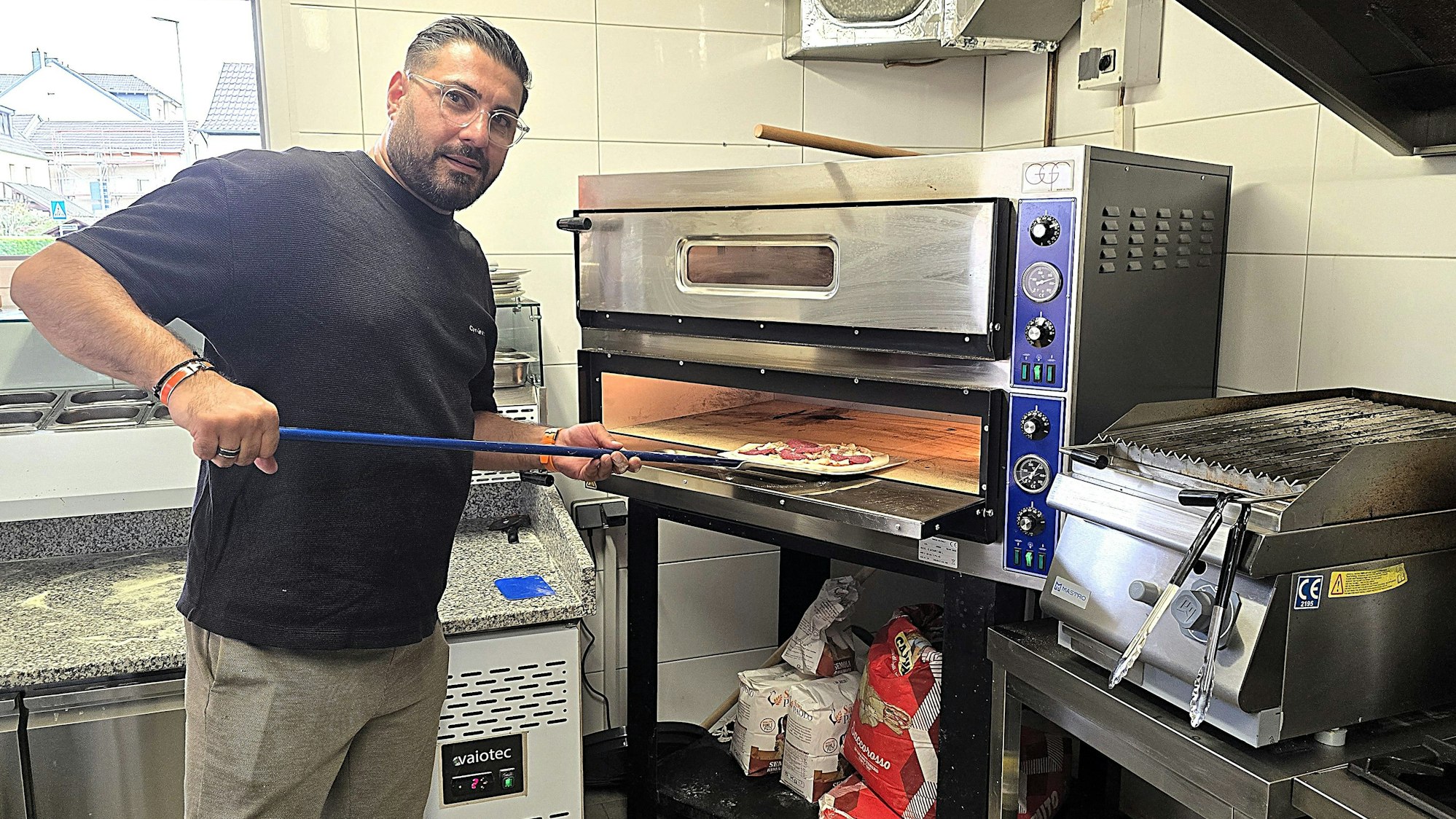 Aziogla Abdulla schiebt die Pizza in den Ofen.