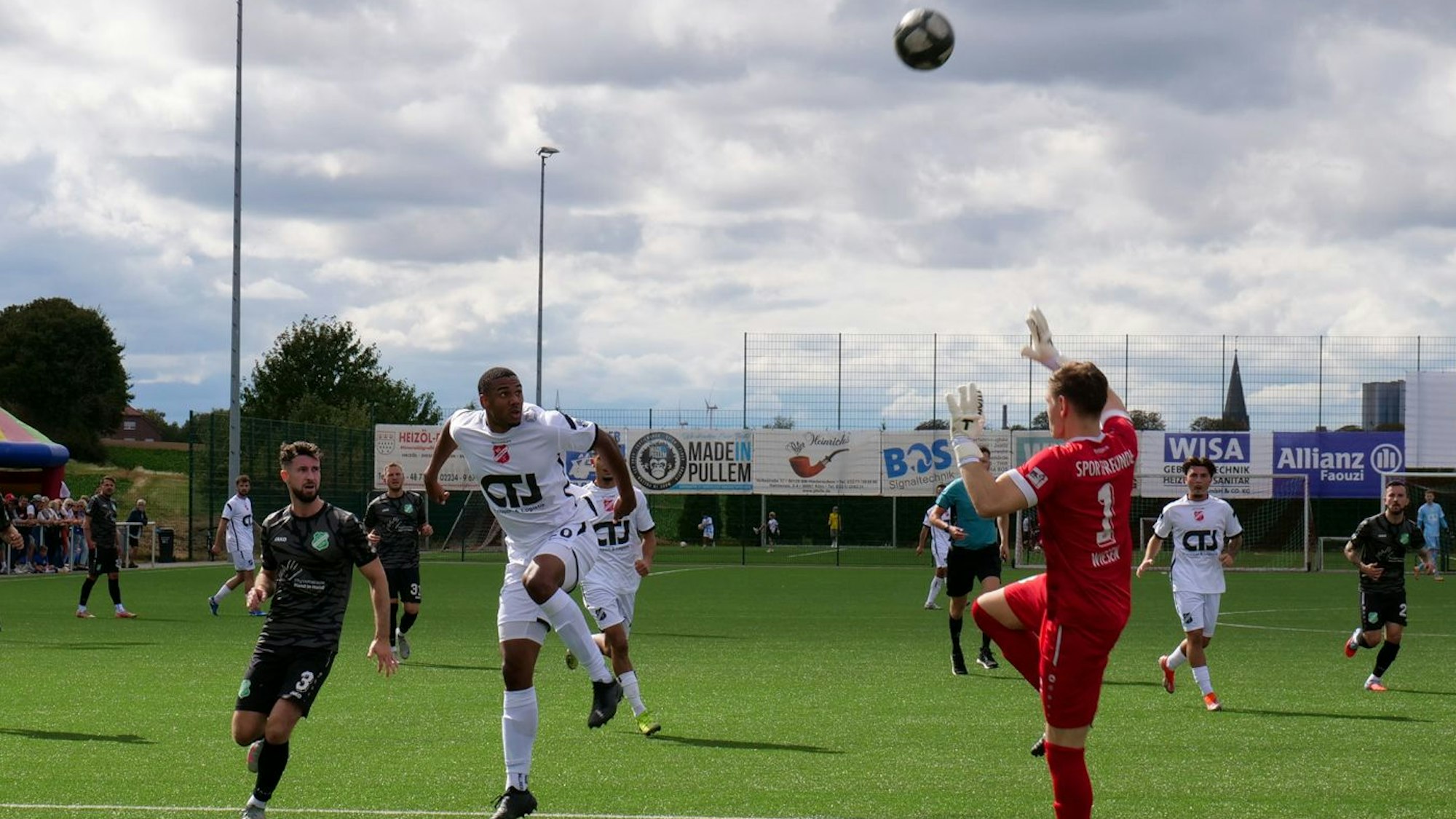Das Foto zeigt einen Fußballer in Weiß, der den Ball über den heranstürmenden Torhüter lupft.
