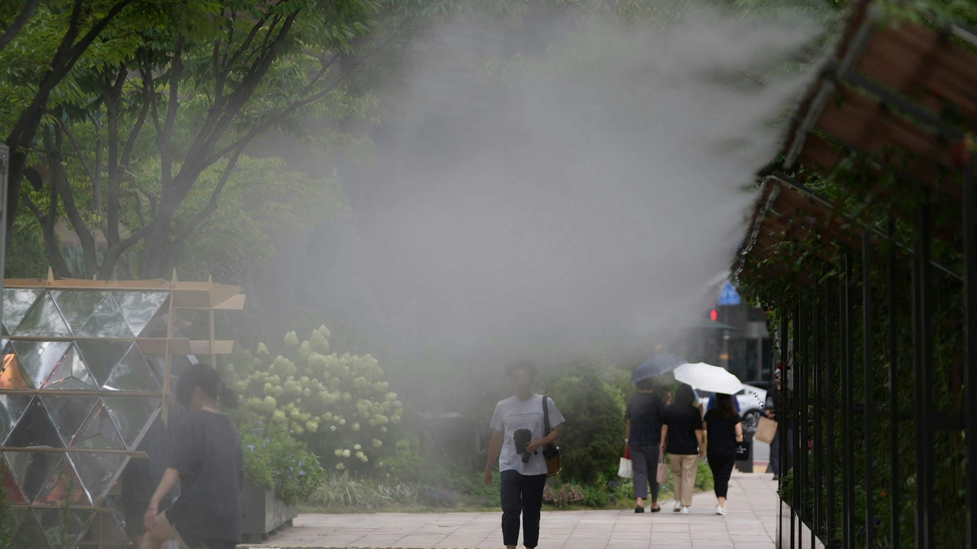 Fußgänger kühlen sich an einer Wasserbefeuchtungsstation in Seoul (Südkorea) ab, die die Stadt aufgrund der Hitzewelle in der Innenstadt von Seoul eingerichtet hat. (Archivbild)
