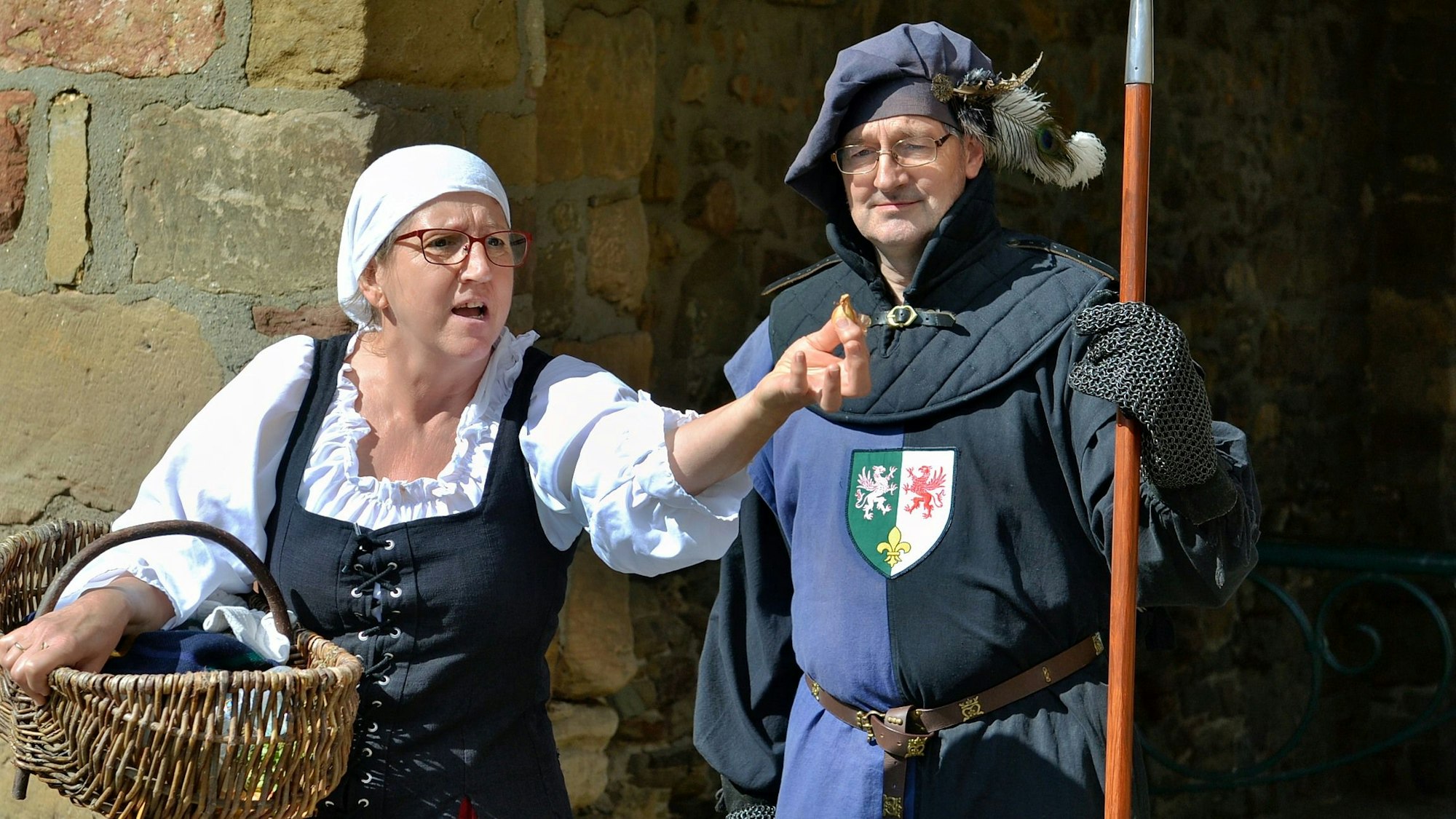 Eine Frau und ein Mann sind bei einer Theateraufführung mittelalterlich verkleidet.