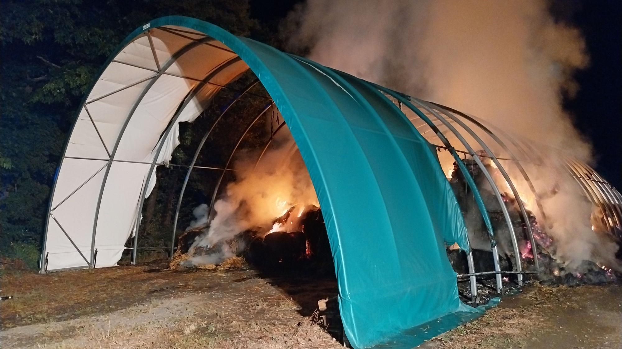 Heuballen brennen unter einer Konstruktion aus Metall und Folie.