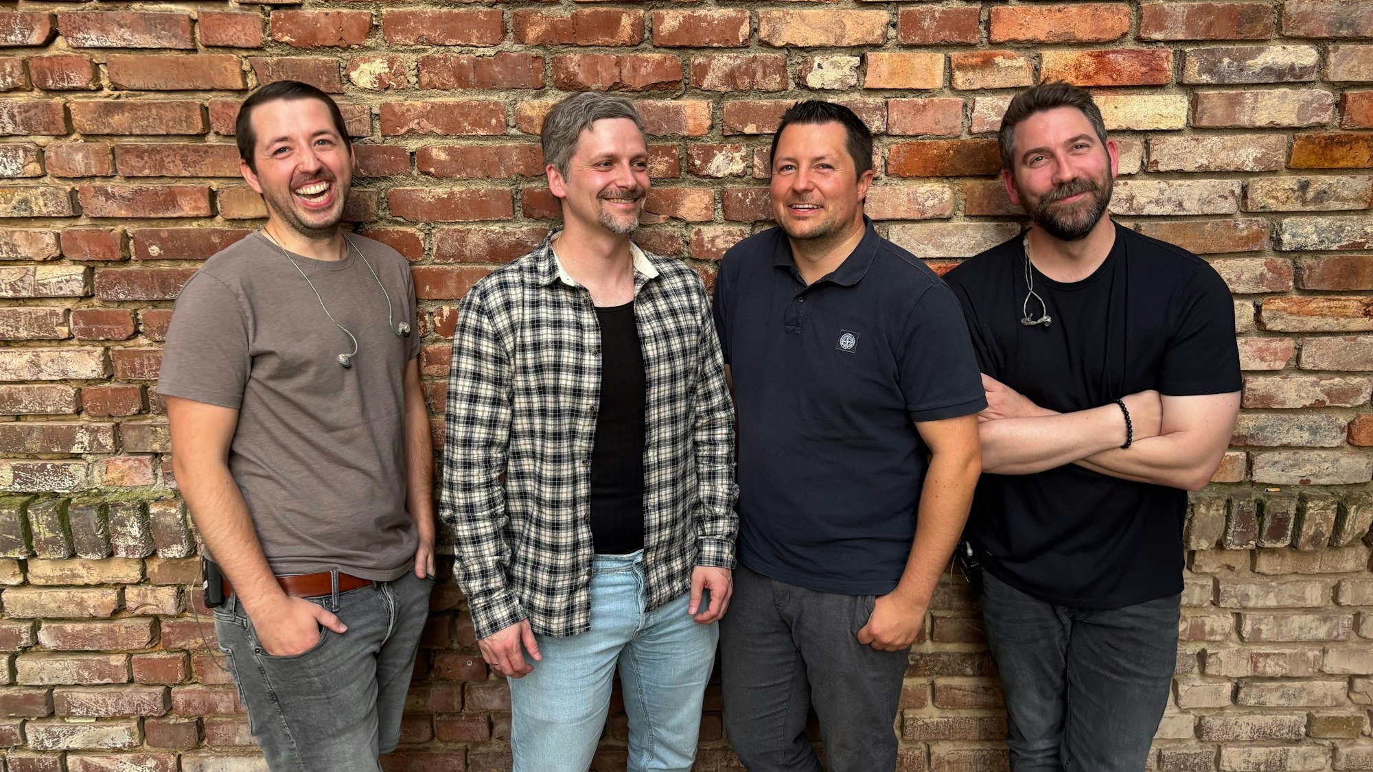 Die vier Bandmitglieder von McConnery lehnen an einer Backsteinwand. Sie machen einen gut gelaunten Eindruck.