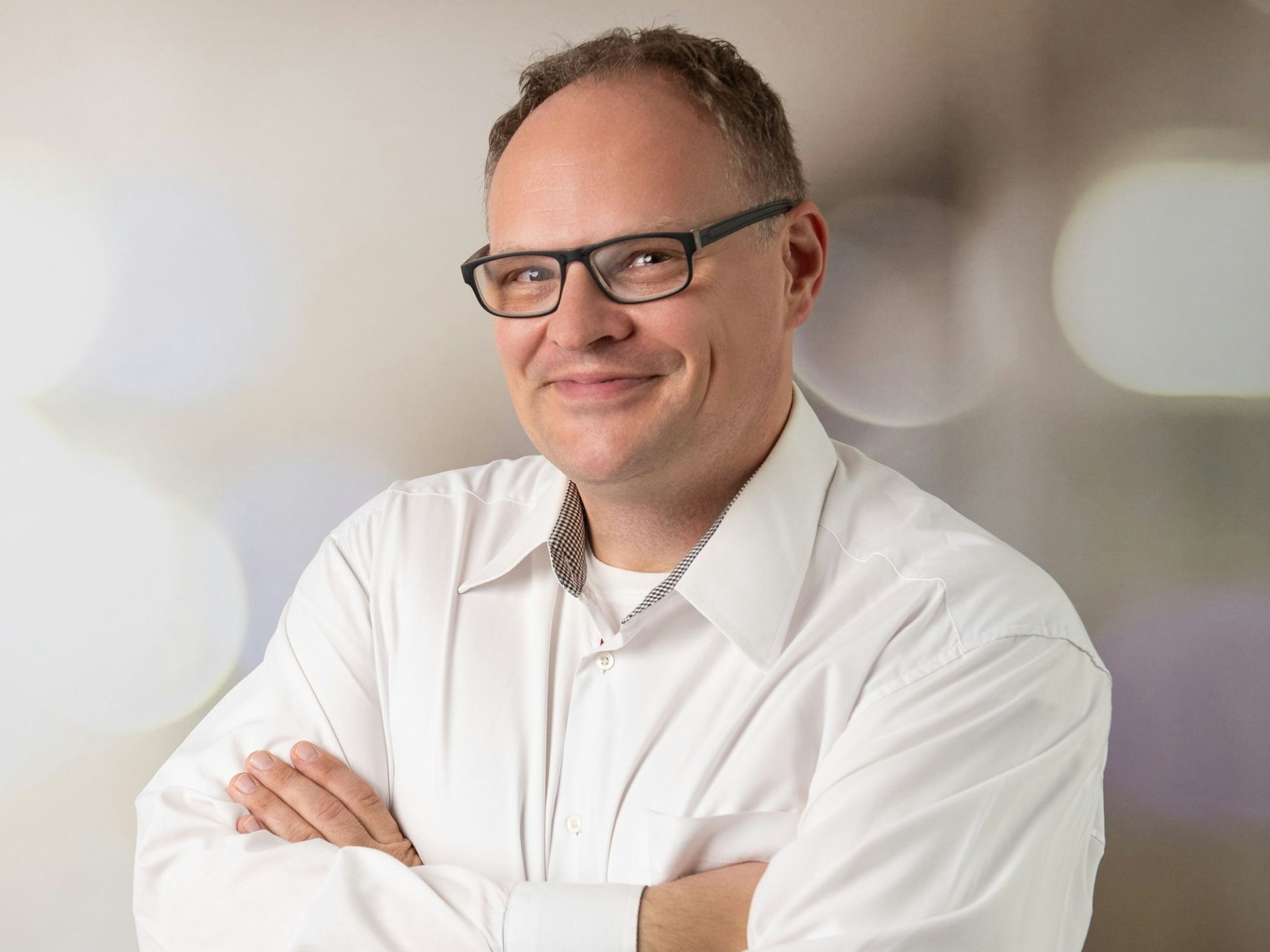 Uwe Wegner hat die Arme vor der Brust verschränkt und grinst.