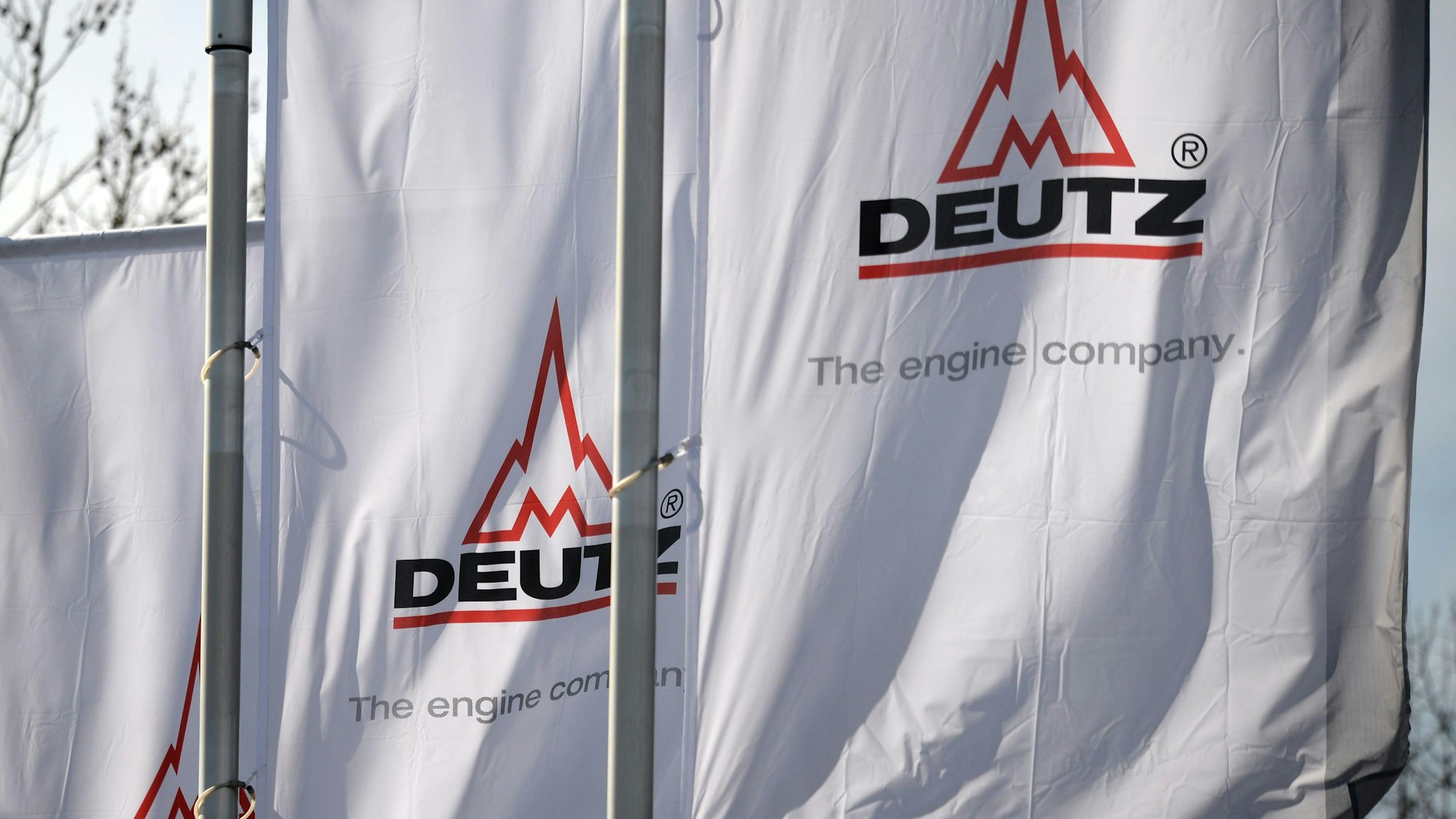 Fahnen mit dem Firmenlogo wehen vor dem Motorenwerk von Deutz in Köln-Porz.