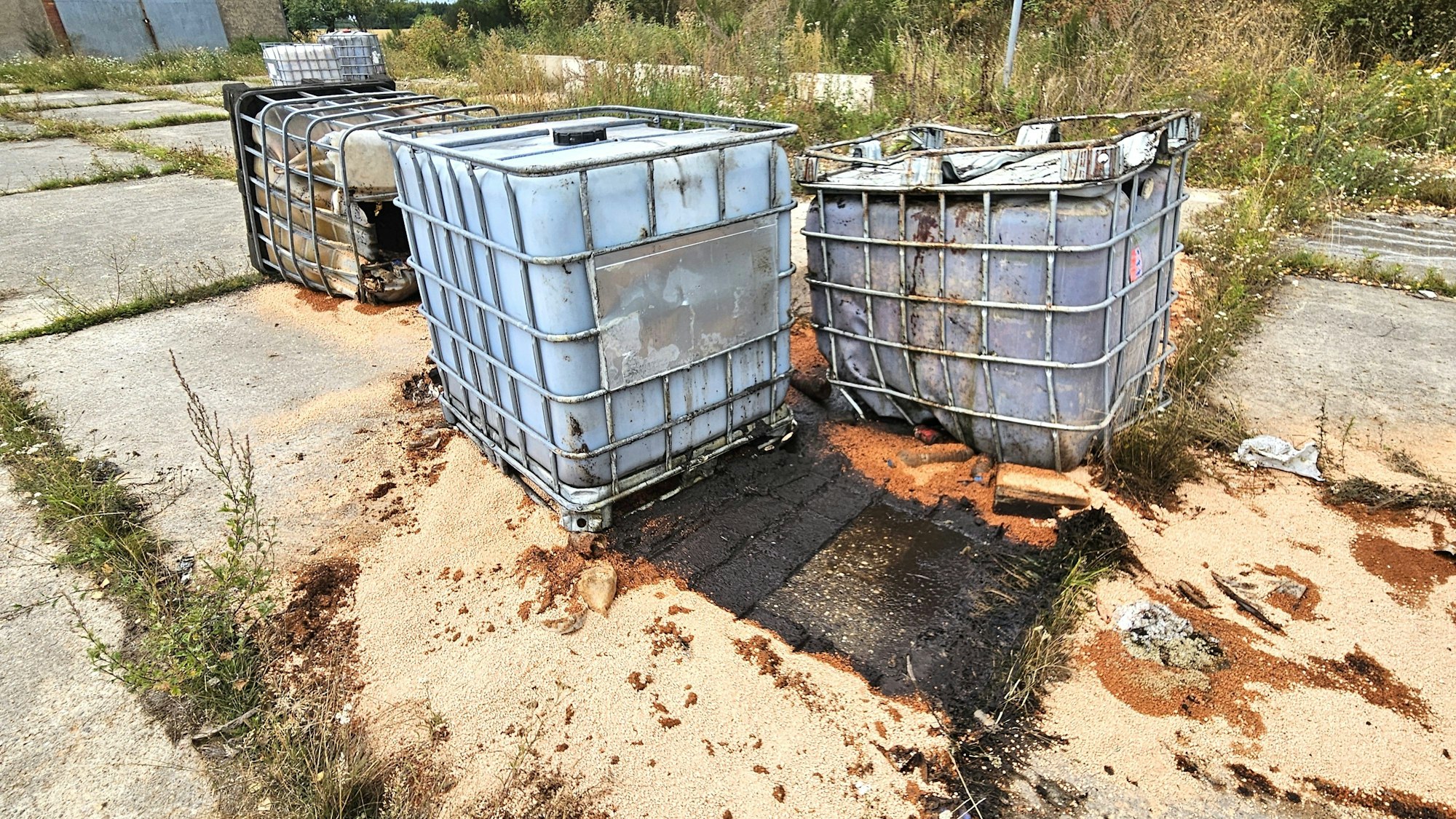 Das Bild zeigt einige Fässer und Öl auf dem Boden.