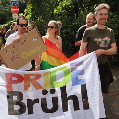 Zu sehen sind Demonstrationsteilnehmer, die ein buntes Banner mit der Aufschrift „Pride Brühl“ tragen.