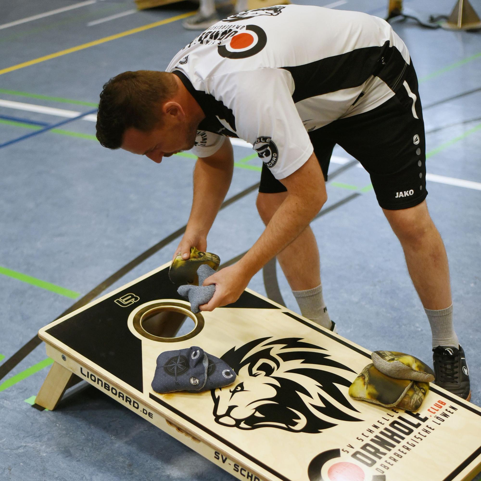 Ein Mann holt ein Säckchen aus dem Spielbrett beim Cornhole.