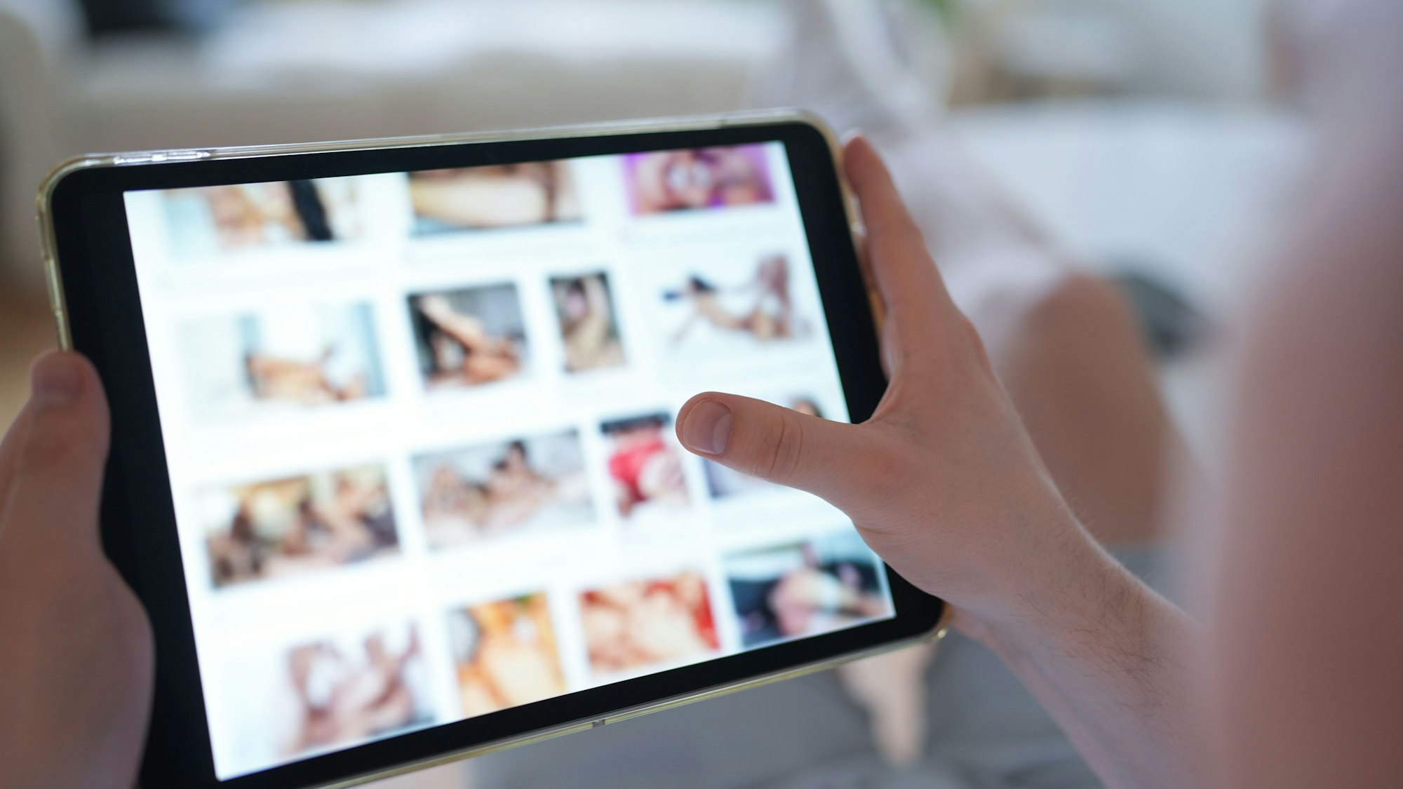 Ein junger Mann schaut sich auf einem Smartphone eine Porno-Internetseite an (gestellte Szene).