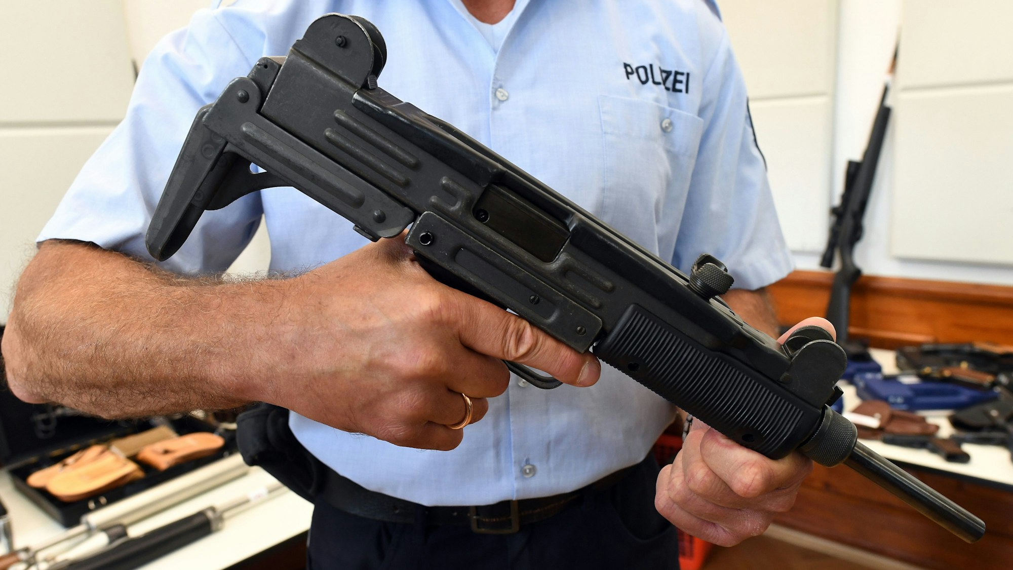 Ein Polizeibeamter hält eine Maschinenpistole vom Typ Uzi in den Händen.