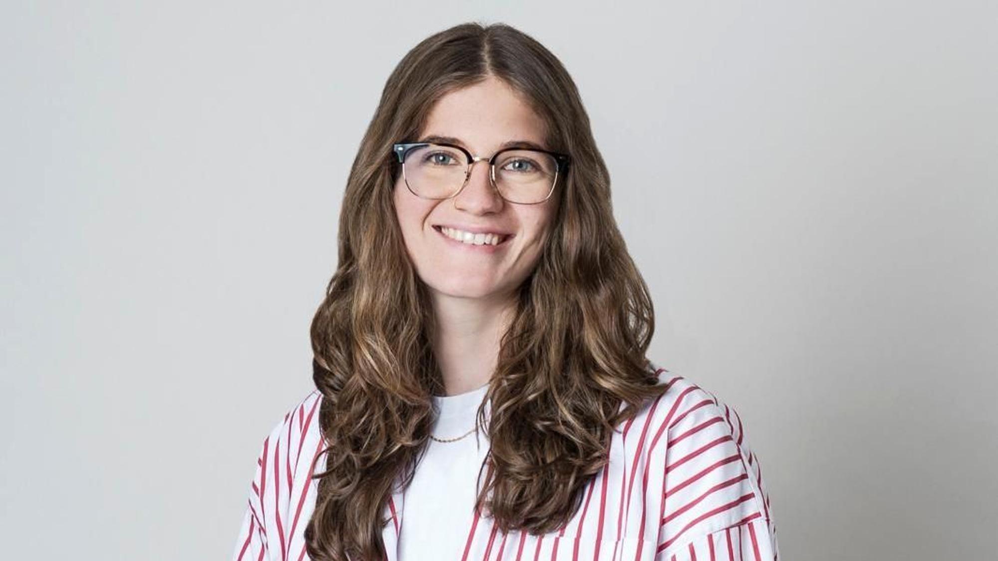 Marie Baum trägt Brille und eine weiße Bluse mit roten Streifen.