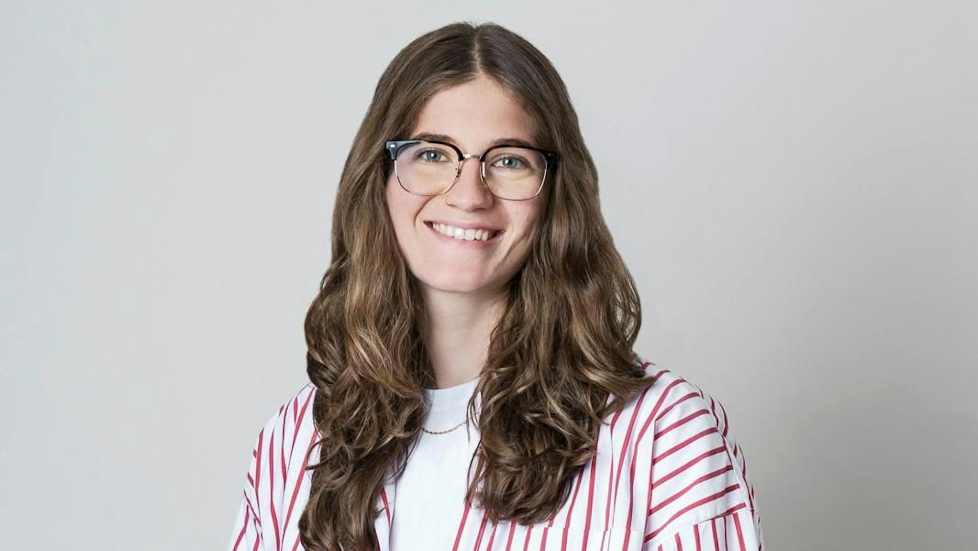 Marie Baum trägt Brille und eine weiße Bluse mit roten Streifen.