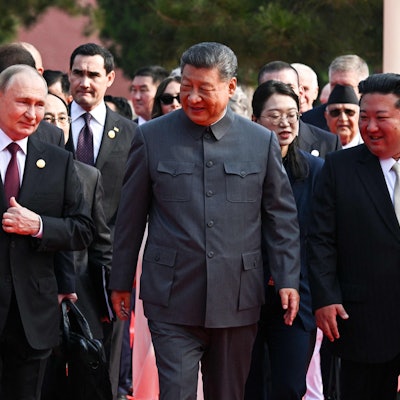 Putin, Xi und Kim gehen lächelnd nebeneinander her.
