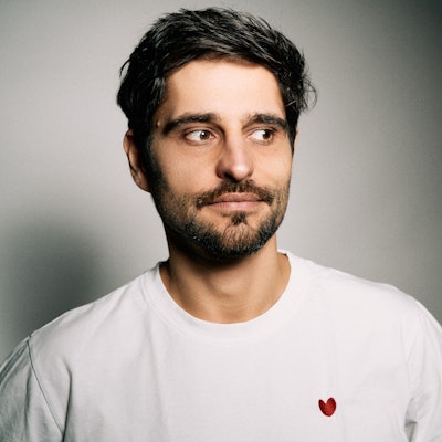 Ein junger Mann mit Bart blickt skeptisch.