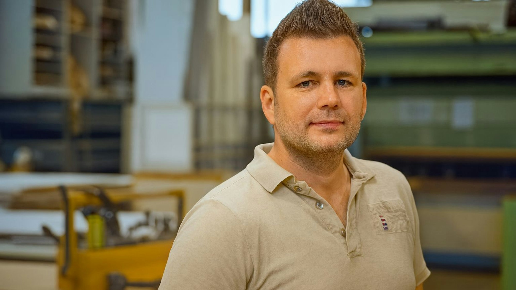 Ein junger Mann im beige Polohemd.