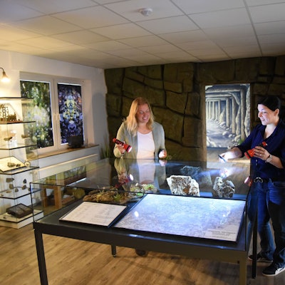 Katja Wonneberger-Kühr (links) und Sarah-Sophie Riedel  beleuchten mit Taschenlampen die Übersichtskarte im ersten der beiden Ausstellungsräume. Im weiteren Verlauf warten Grubenwerkzeuge, Erinnerungsstücke und auch Münzen aus Wildberger Silber auf die Besucher.