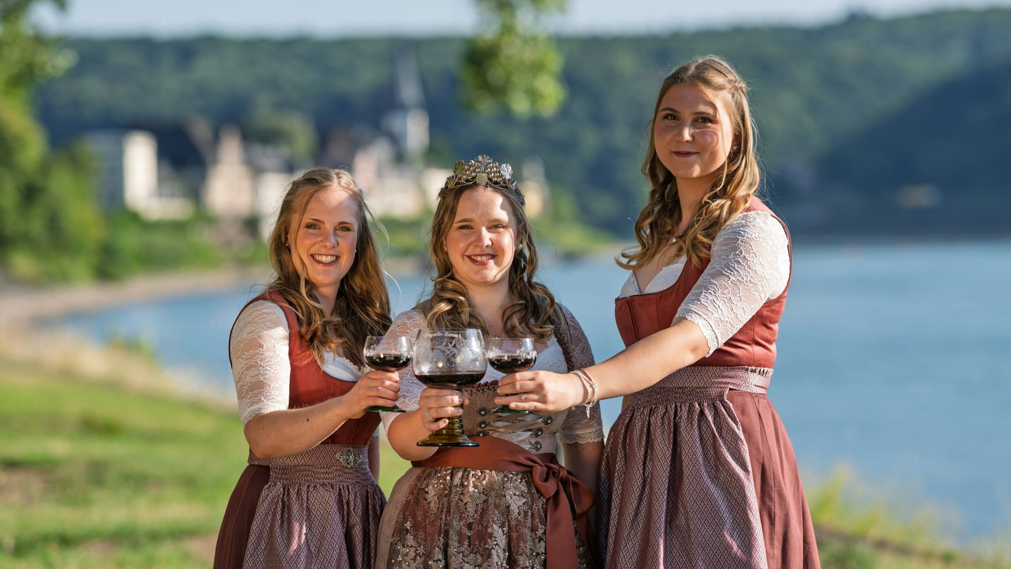 Drei junge Frauen mit Weinkelchen, im Hintergrund der Rhein.