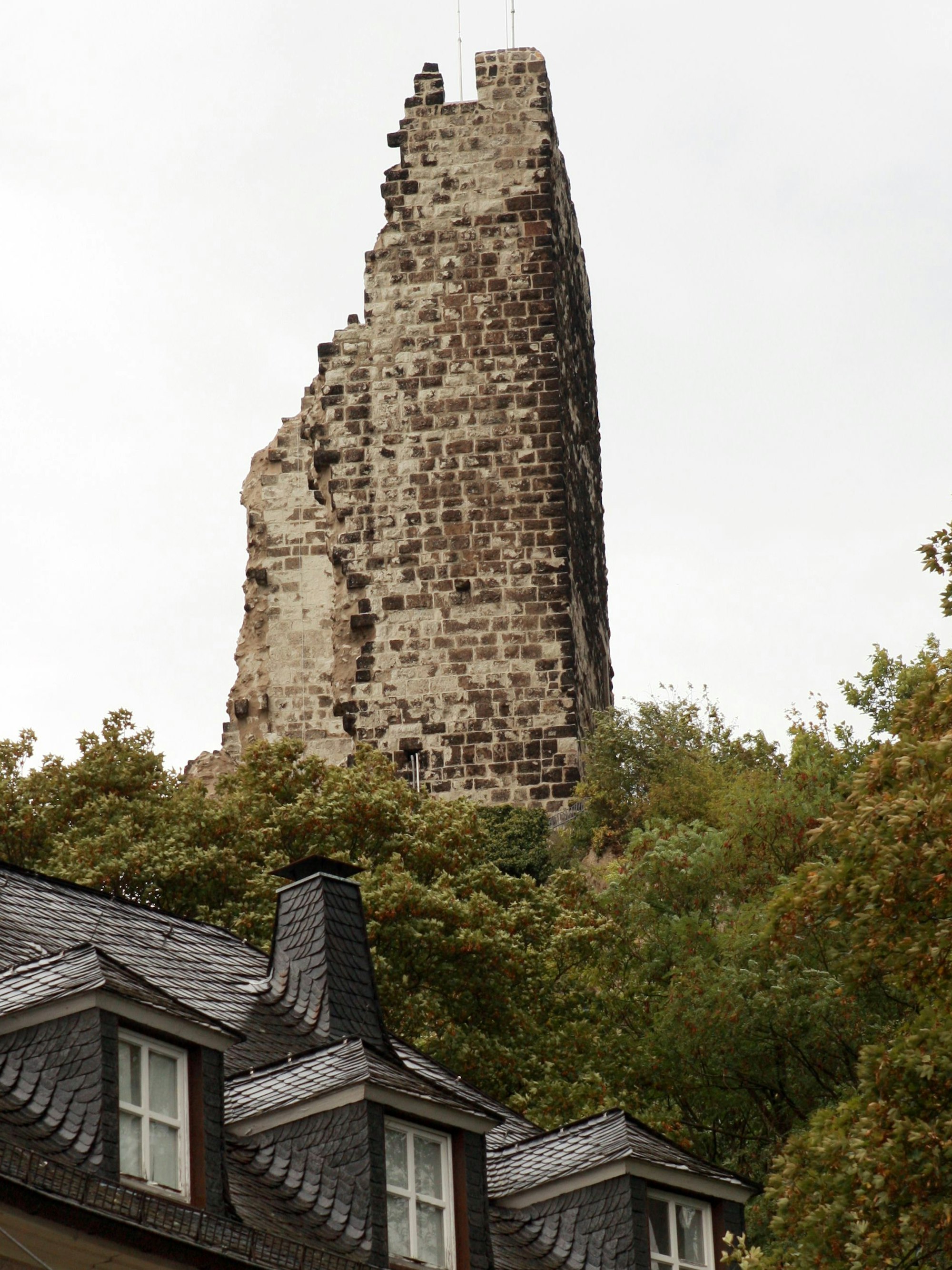 Über einem Dach eines Hauses ist eine Ruine zu sehen.