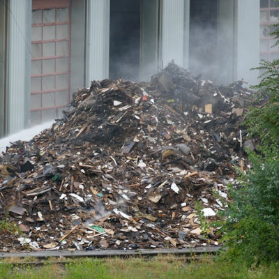 Die Feuerwehr schichtete den brennenden Sperrmüll vor der Halle in Troisdorf auf, um ihn draußen ablöschen zu können.