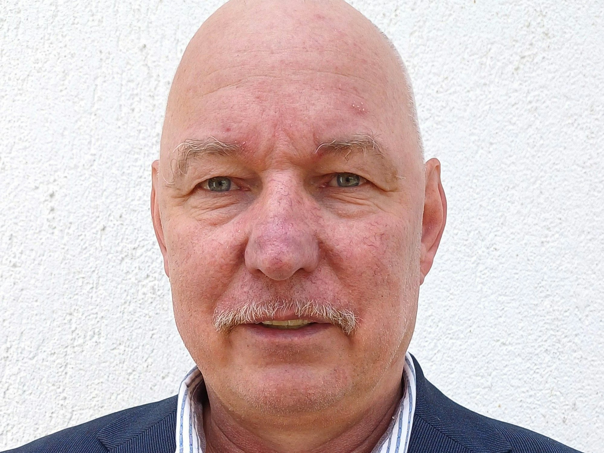 Porträtbild von Harry Deutsch. Er trägt ein Hemd mit hellblauen Streifen und ein Sakko.