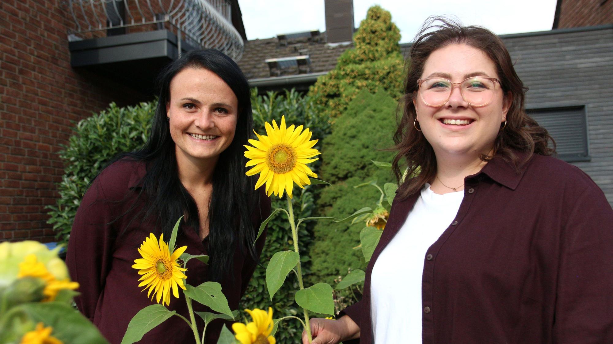Das Foto zeigt zwei Frauen mit Sonnenblumen in den Händen.