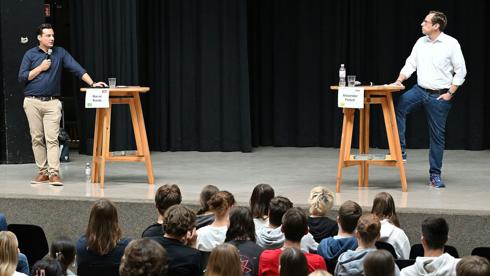 Die beiden Kandidaten stehen sich an zwei Stehtischen gegenüber.