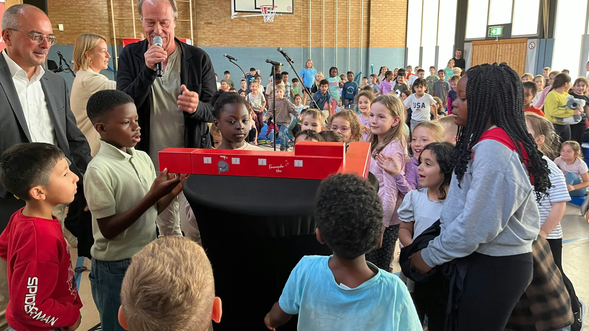 Staunend betrachten die Kinder das Miniatur-Modell von Mobi. Mit ihnen freuen sich Gero Wiesenhöferund Wolfgang Schmitz (v.l.).