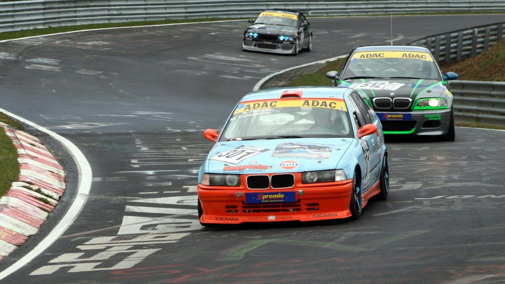 Drei Rennautos fahren auf der Strecke des Nürburgrings.