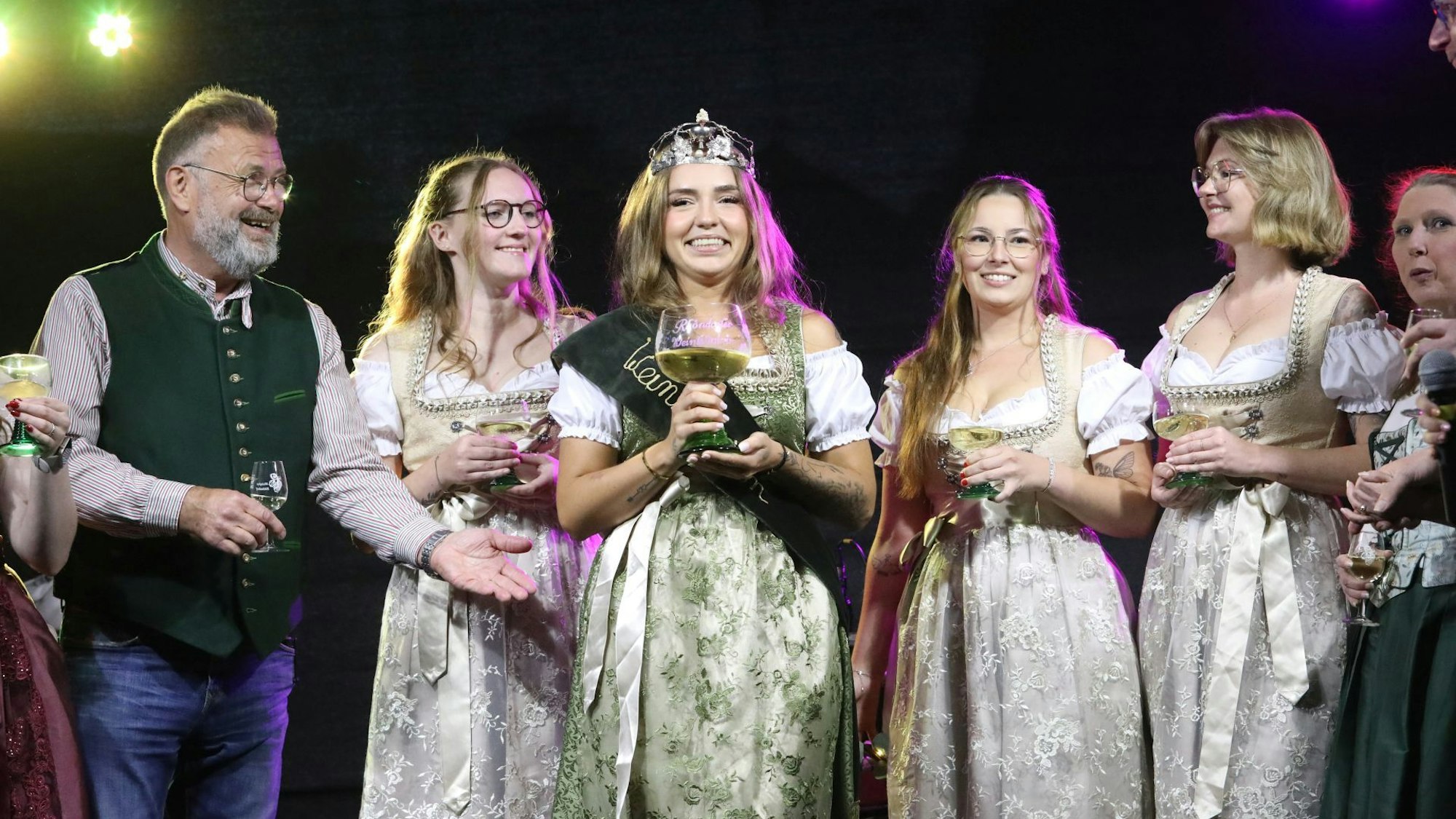 Ein Mann neben vier jungen Frauen in festlichen Kleidern.
