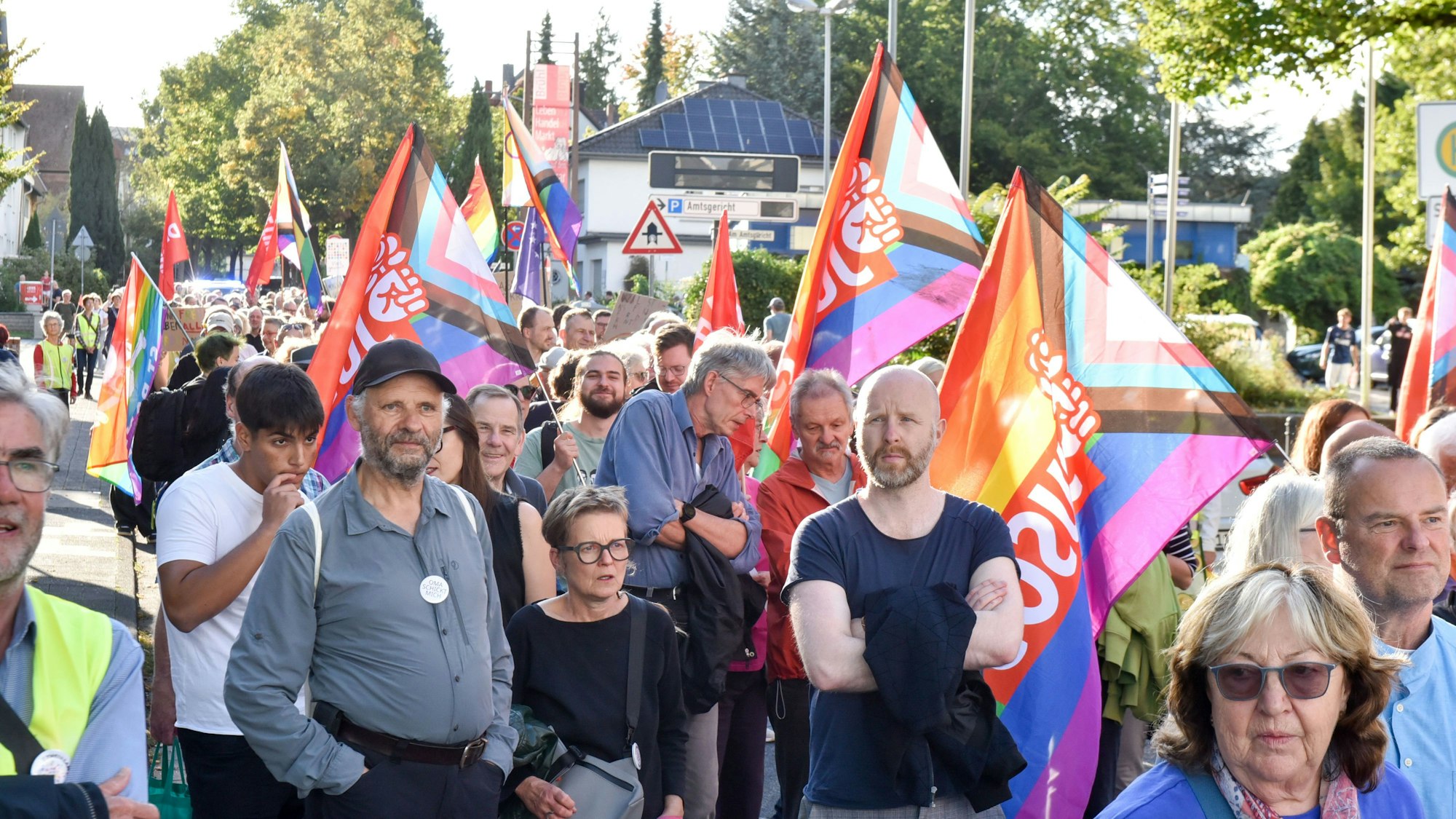 Auf dem Bild sind Demonstranten mit bunten Fahnen zu sehen.