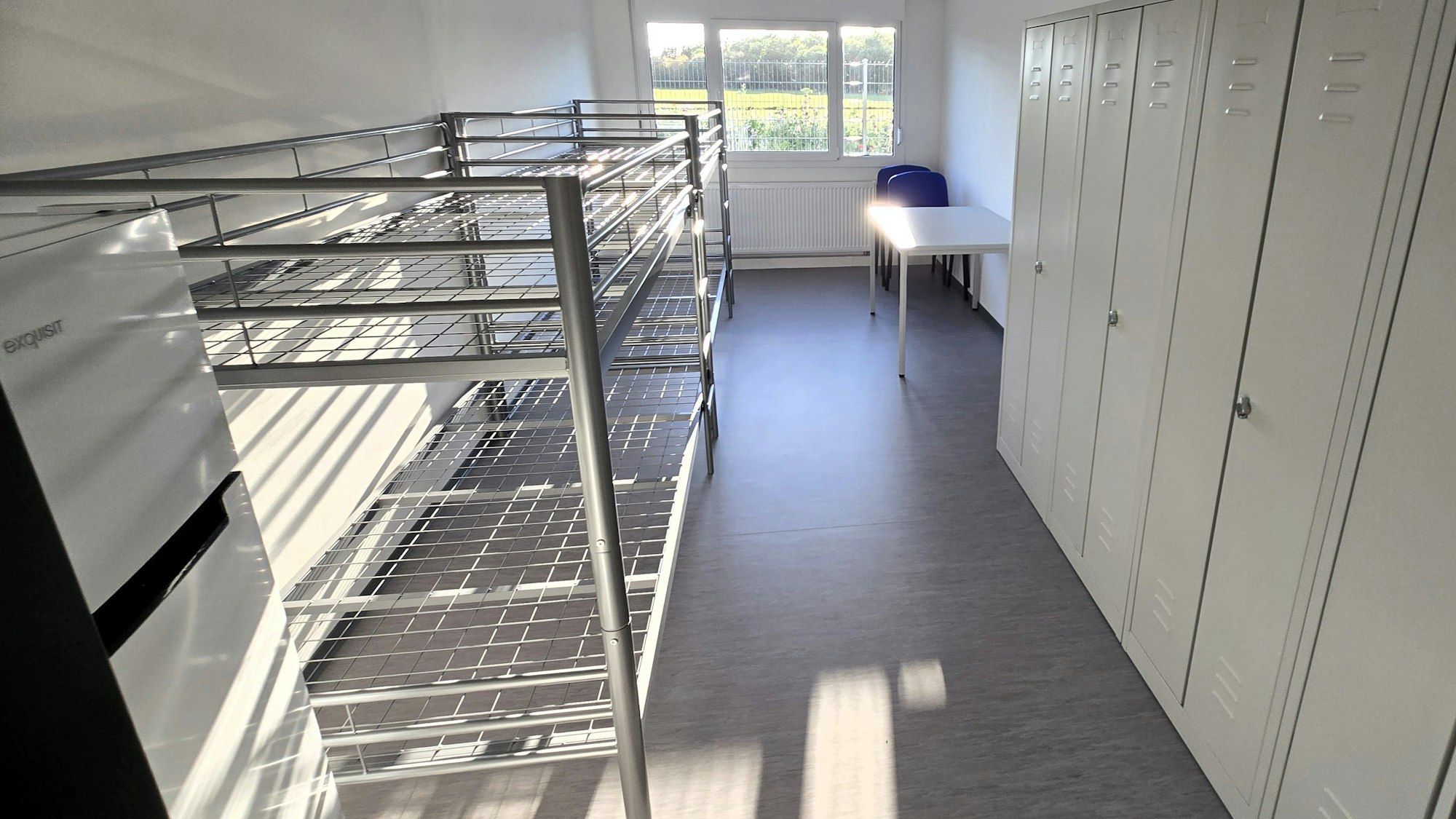 In den 18 qm großen Wohnräumen der Containeranlage sind bis zu vier Personen vorgesehen. Ausgestattet mit vier Betten, einem Tisch mir Sitzgelegenheiten, Schänken und ein Kühlschrank.