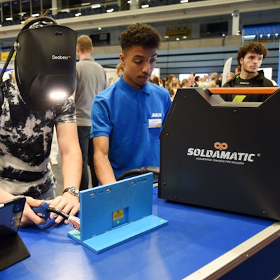 Ein junger Mann mit Schweißerhaube hantiert mit einem technischen Gerät.