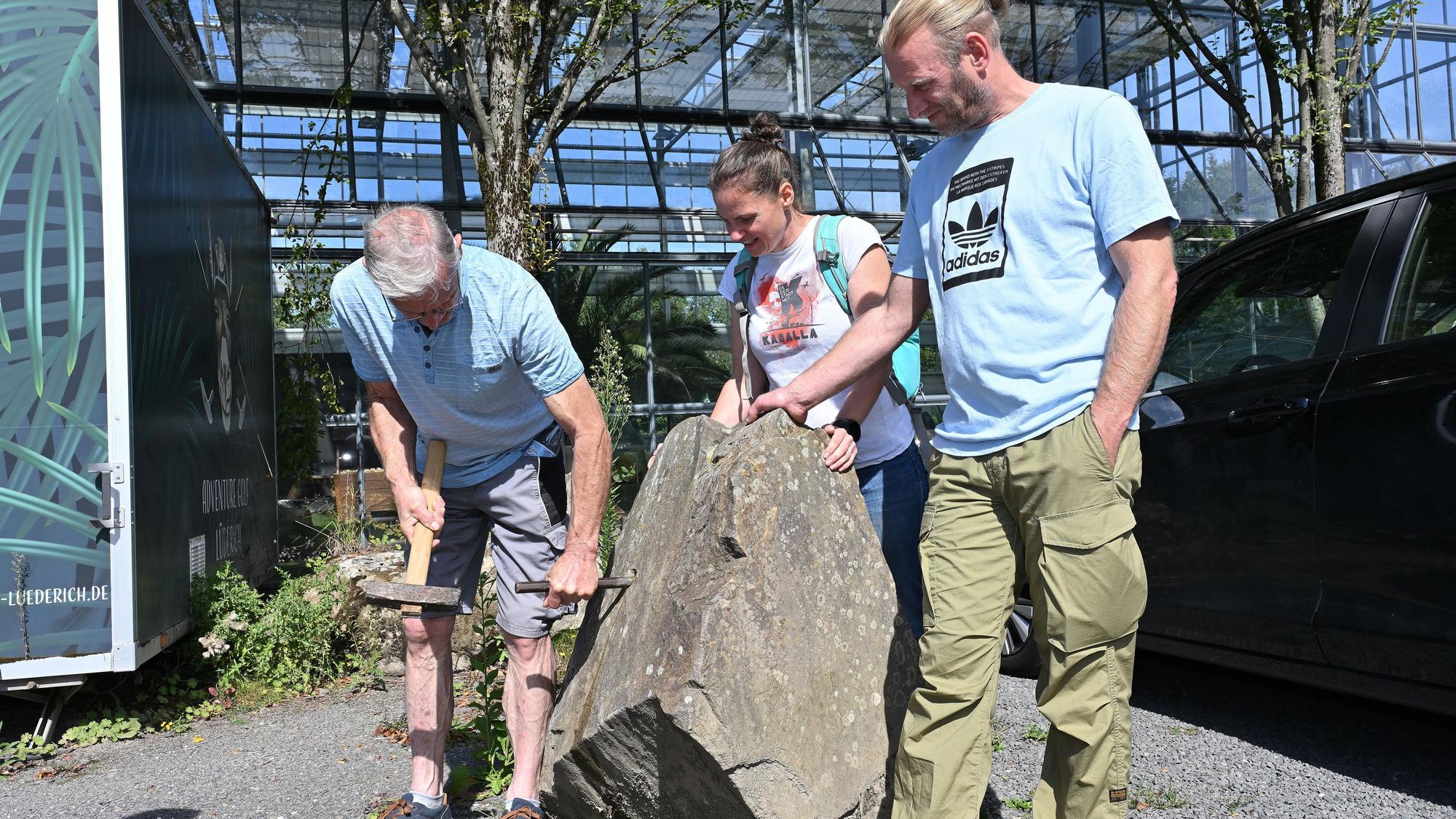 Eine Gruppe Wanderer steht um einen Stein herum, einer Haut mit einem Hammer auf einen Meißel.