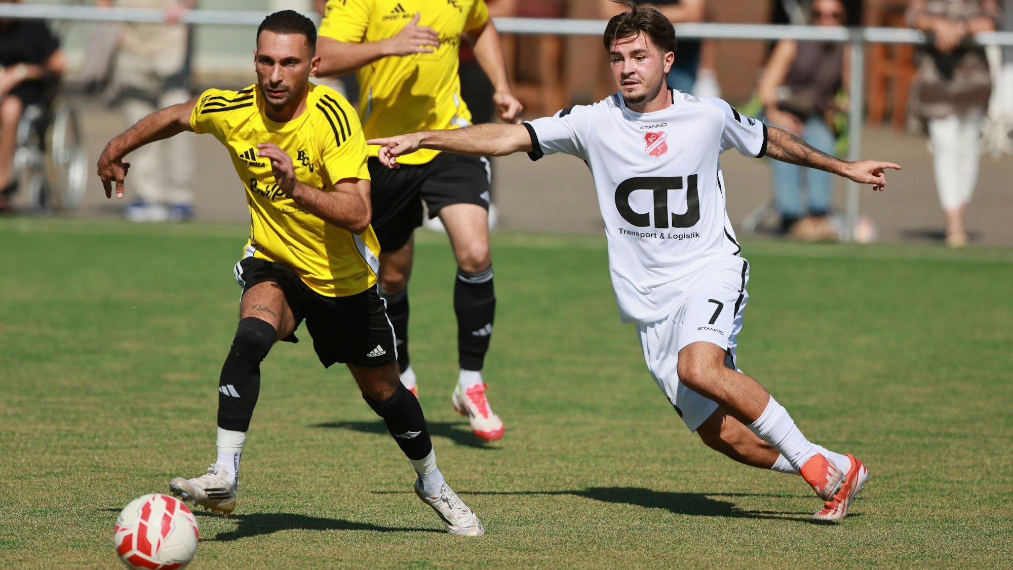 Das Foto zeigt einen Fußballer im hellen Trikot, der sich von seinem Gegenspieler im Zweikampf nicht beeindrucken lässt.