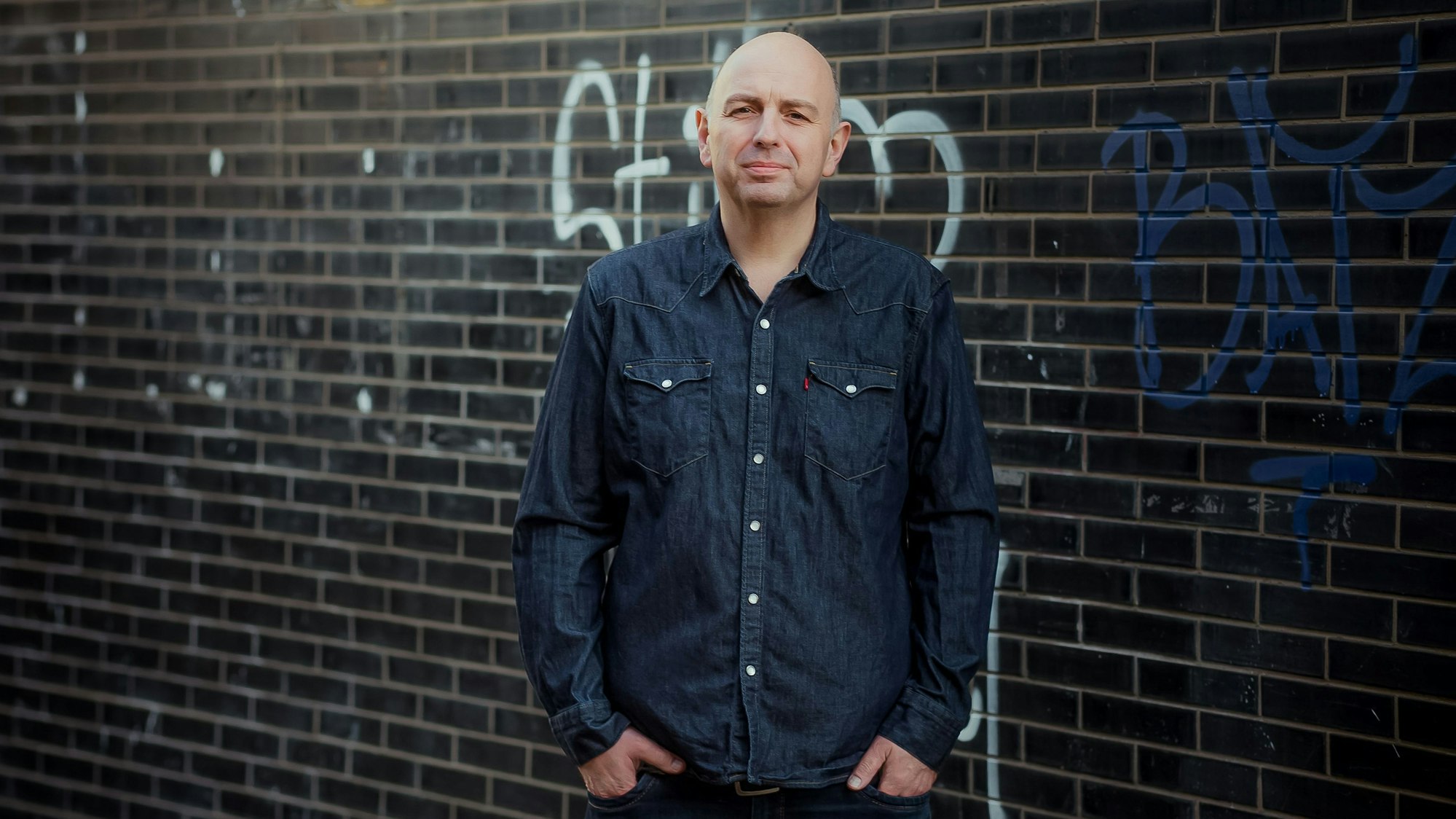Das Bild zeigt den Autor vor einer Mauer.