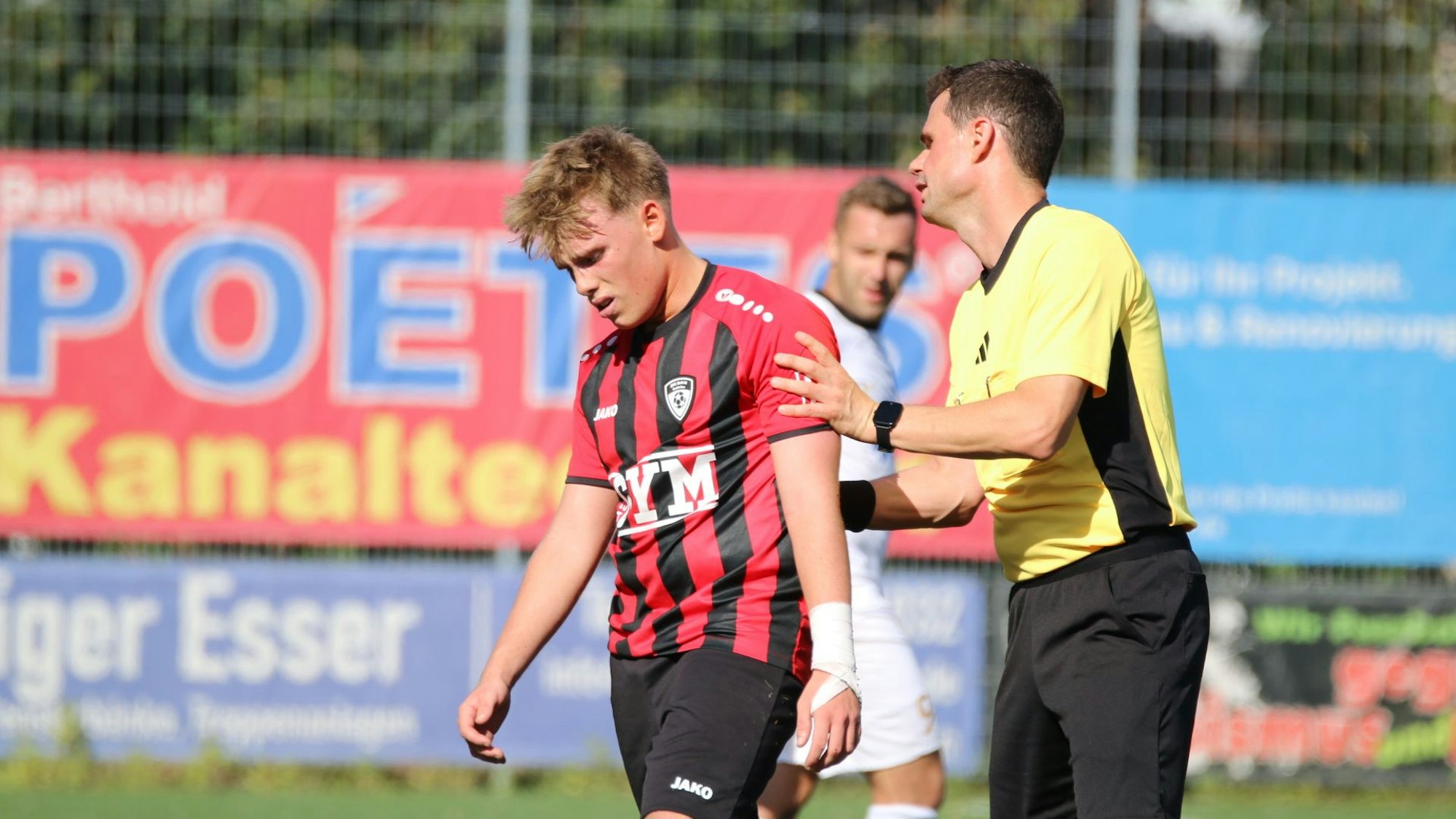 Spieler Rick sieht enttäuscht aus, der Schiedsrichter redet ihm gut zu.