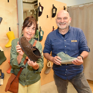 Michael Hiß (Nordwolle) und Barbara Papst von Wildling Shoes halten Schuhe in einem Showroom in den Händen.
