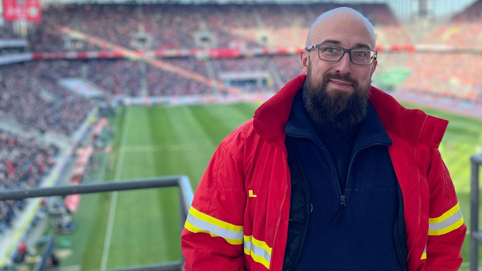 Auf dem Bild ist ein Mann in DLRG-Uniform auf der Tribüne des Rhein-Energie-Stadions zu sehen.