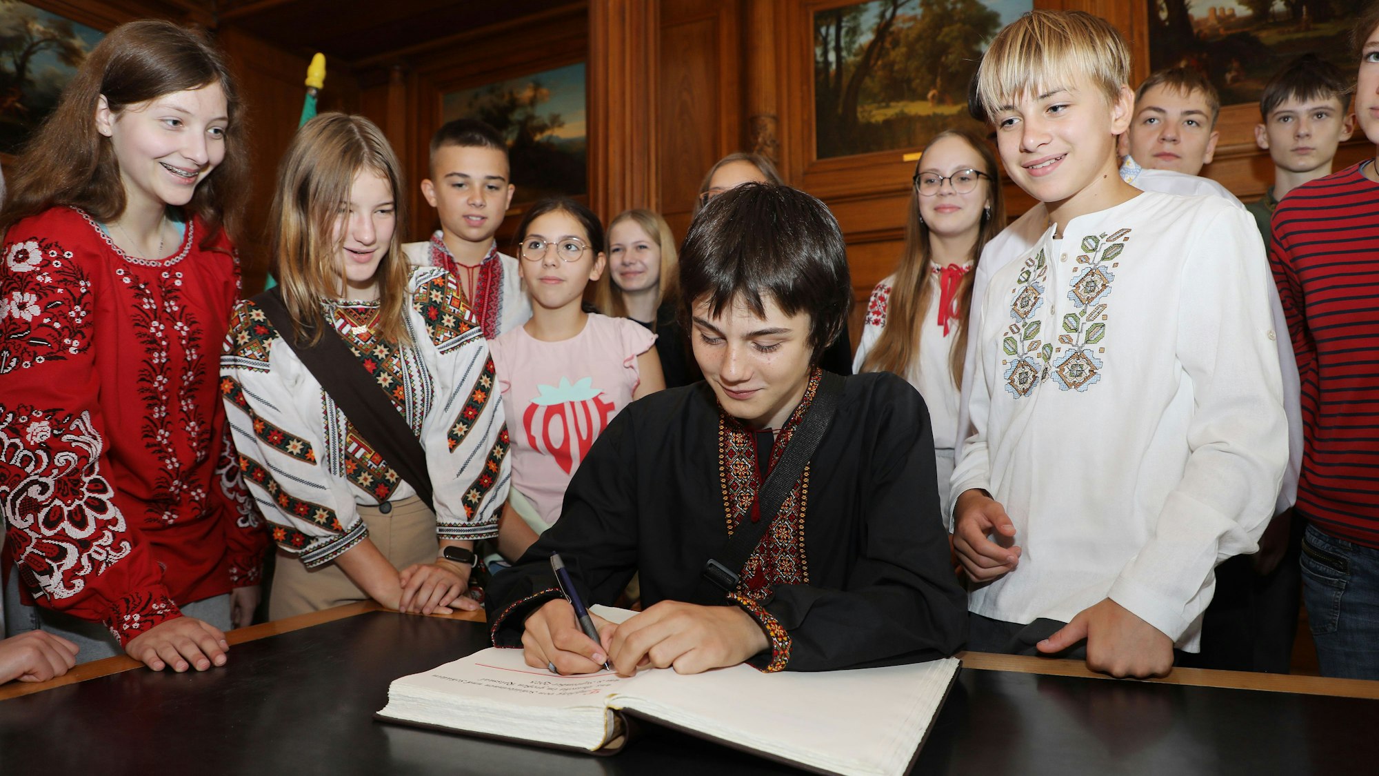 Der 14-jährige Jura zeigt, wie es mit dem Eintrag ins Goldene Buch der Stadt Bergisch Gladbach geht. Er ist schon zum dritten Mal bei einer Schülerfahrt in die Partnerstadt dabei.
