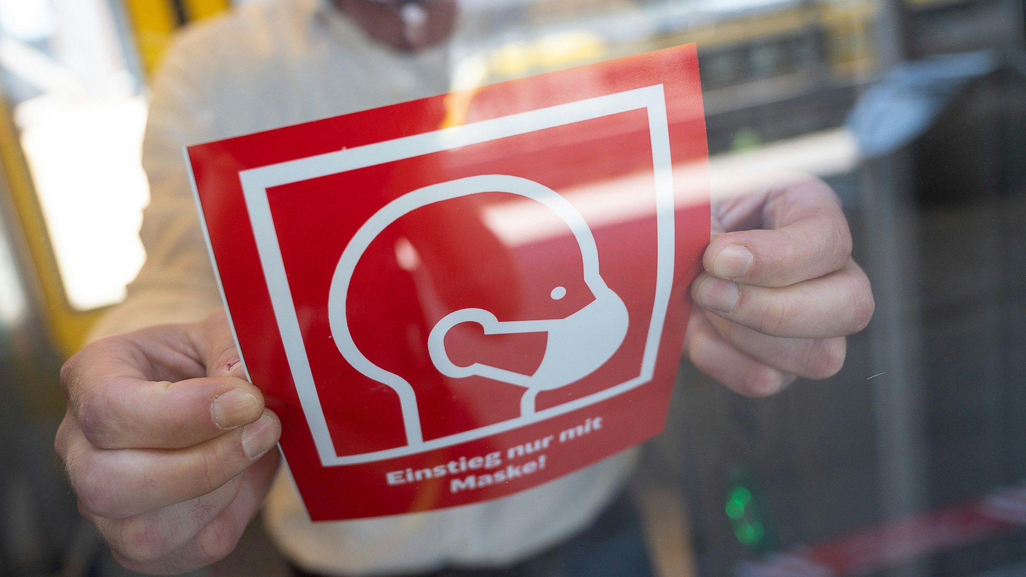 ARCHIV - 07.08.2020, Baden-Württemberg, Stuttgart: Ein Mann bringt während eines Pressetermins, bei dem neue Hinweistafeln zur Maskenpflicht in Zügen und Bahnhöfen vorgestellt werden, einen der Hinweise, auf dem «Einstieg nur mit Maske» steht, an einem Zug an.