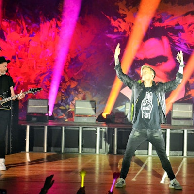 Billy Andrews steht auf der Bühne und reckt beide Arme in die Höhe.