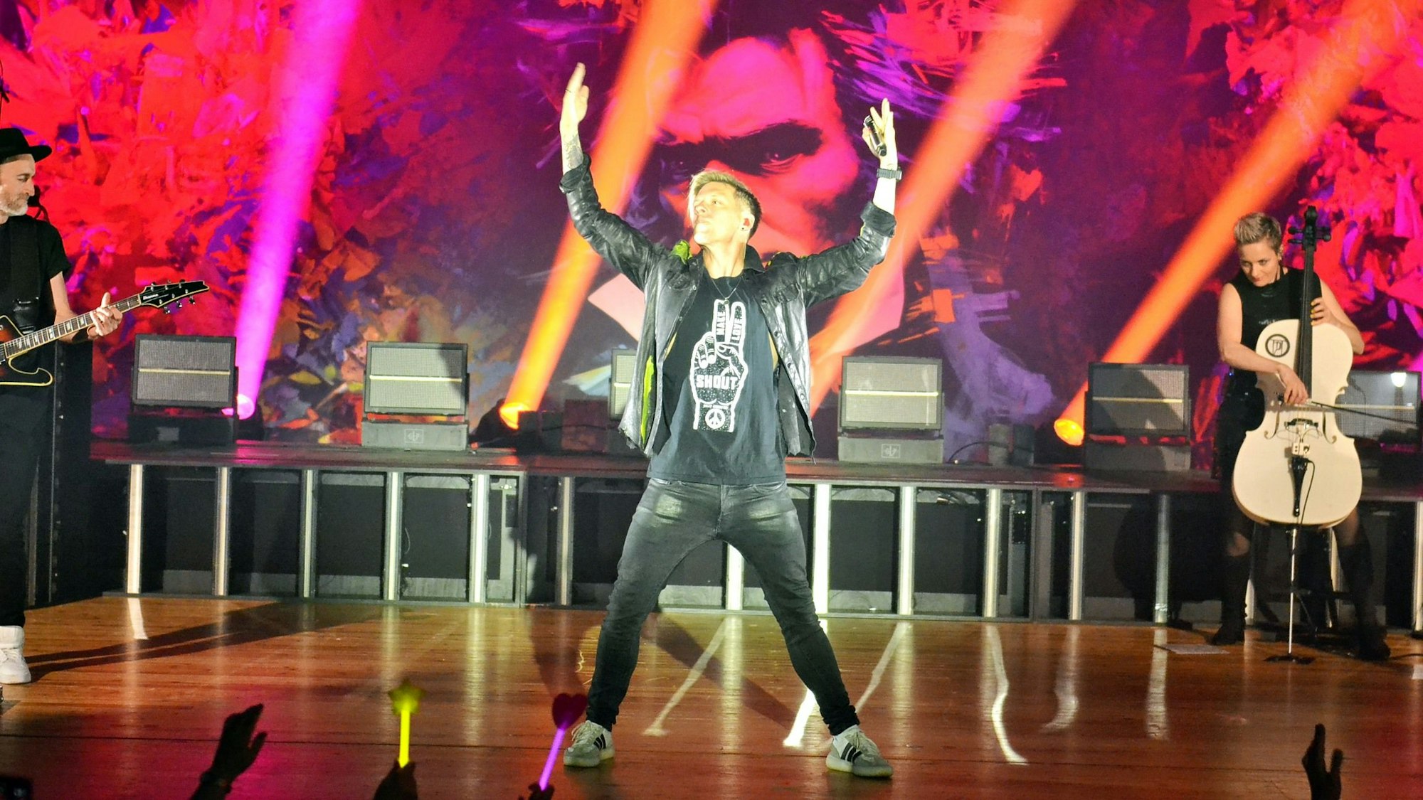 Billy Andrews steht auf der Bühne und reckt beide Arme in die Höhe.