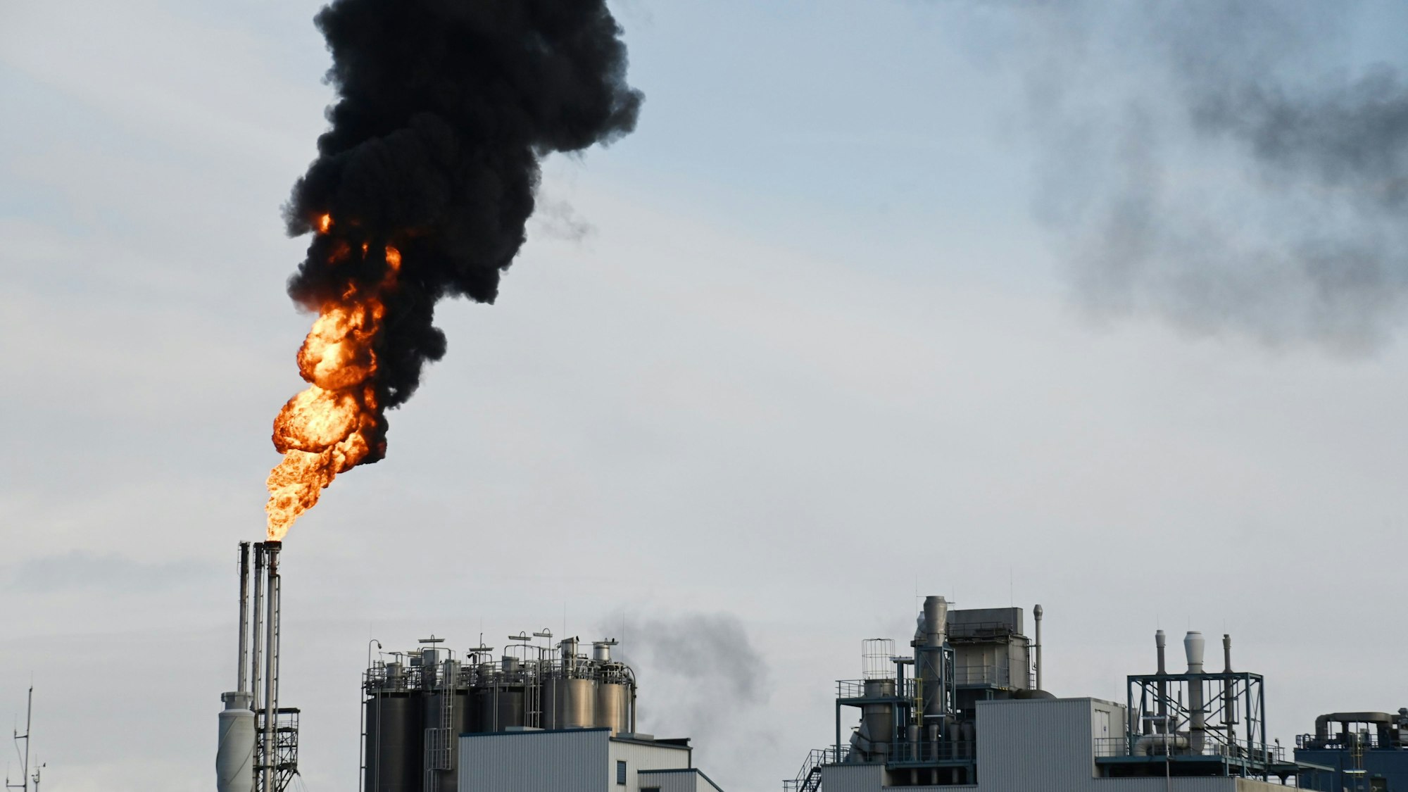 Zu sehen ist die Fackelanlage, aus der eine Flamme und schlägt und Rauch entweicht.