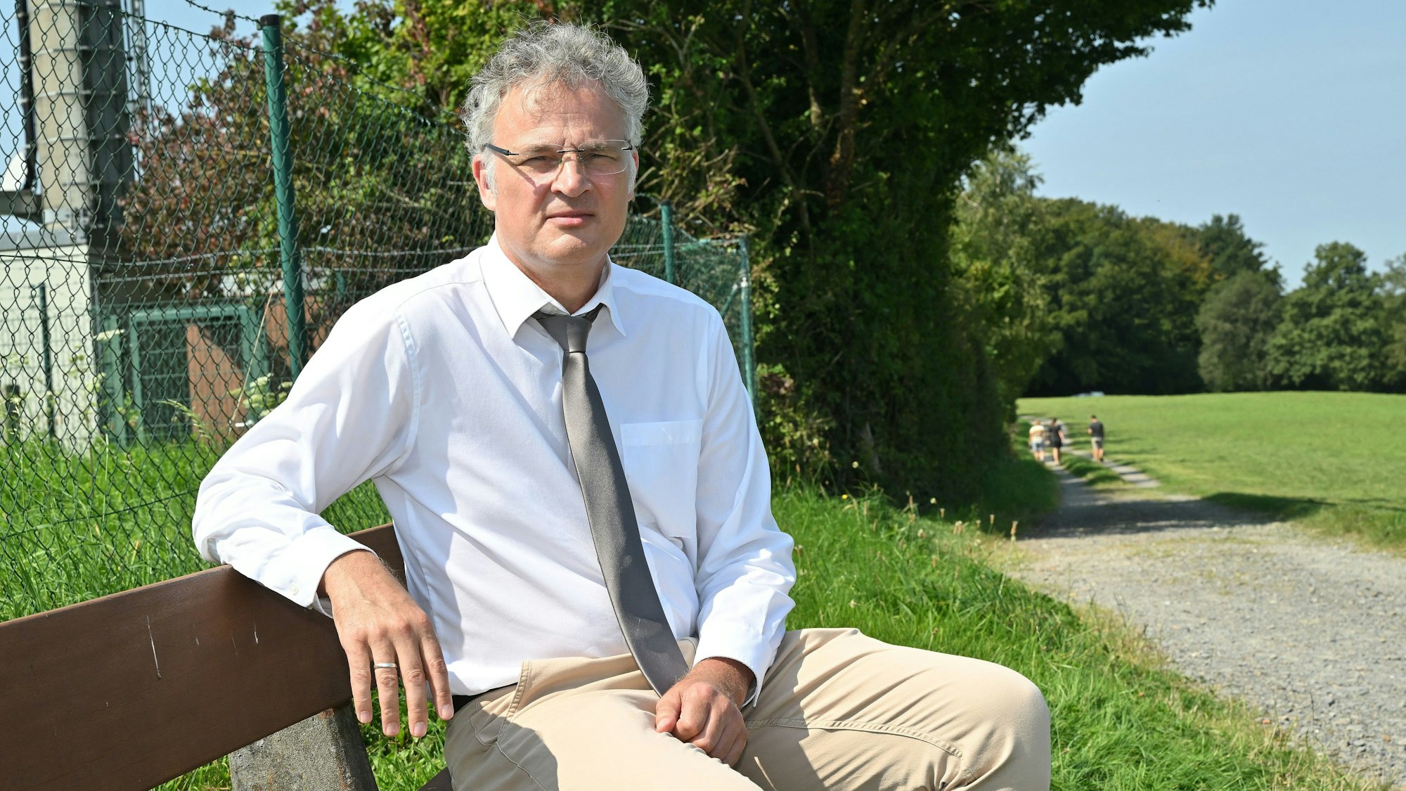 Sebastian Weirauch (AfD) sitzt auf einer Bank in einem Park.