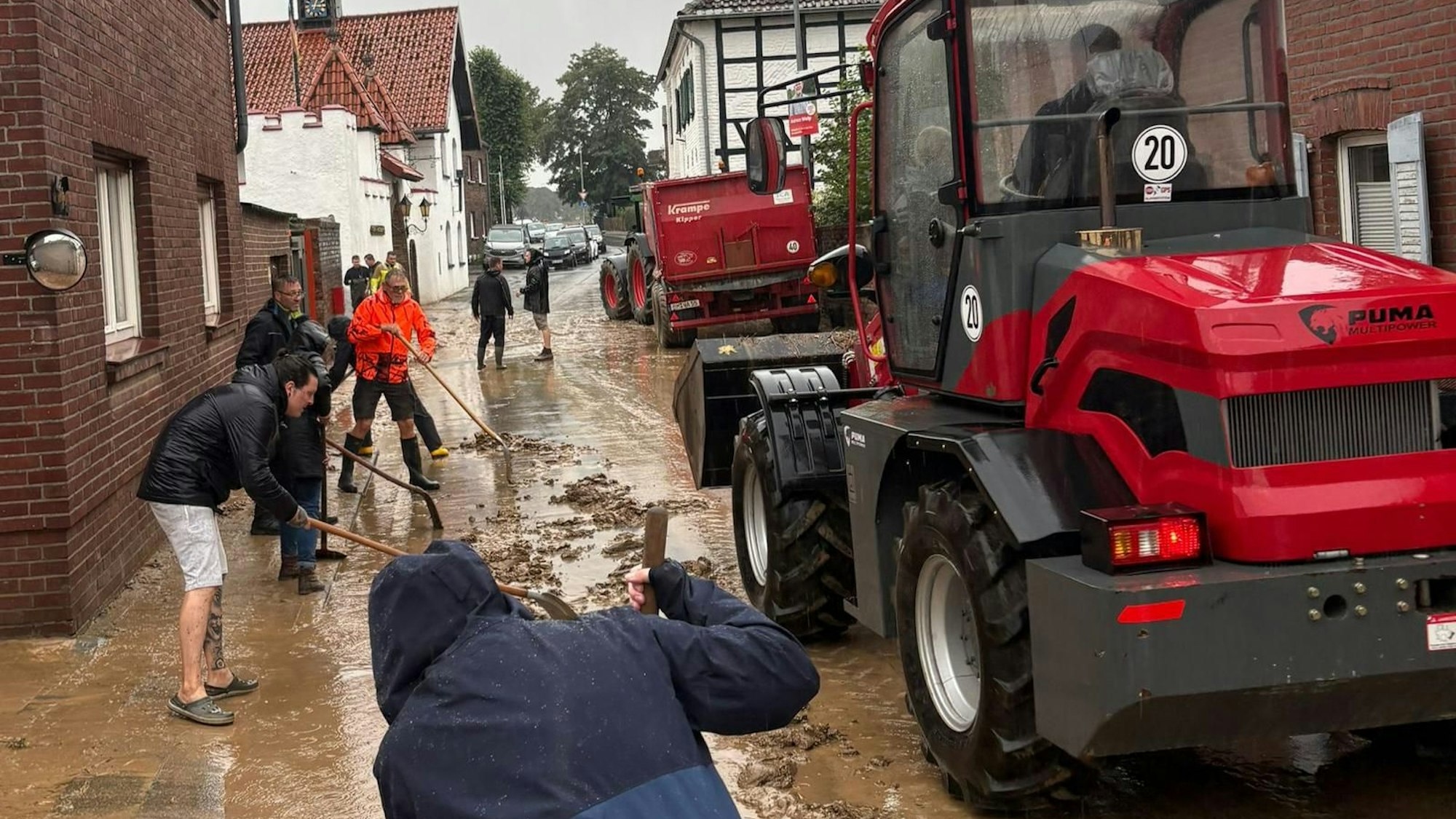 Auf dem Bild sind Helfer mit Schaufeln und zwei Traktoren zu sehen.