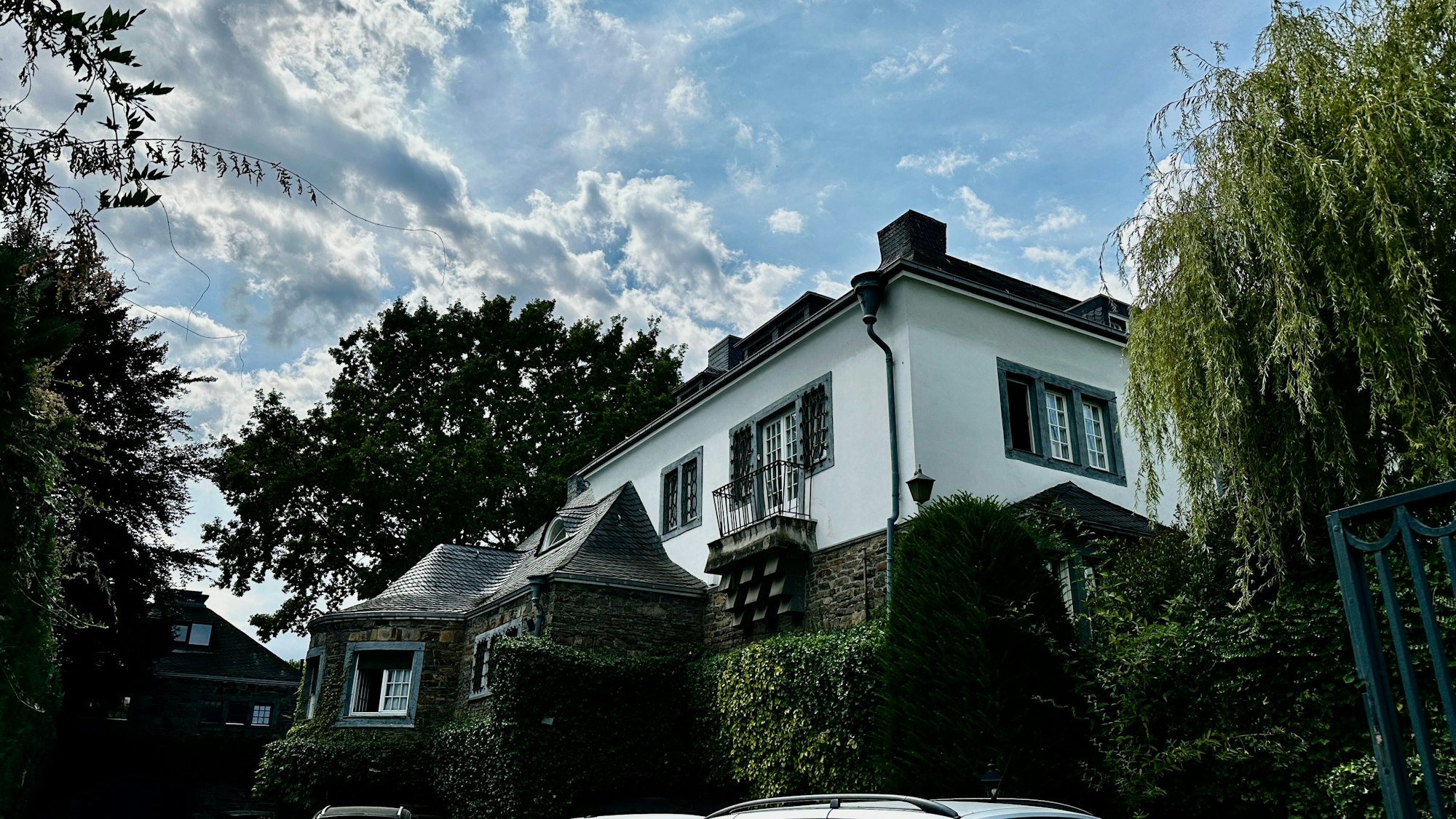 Eine große Villa mit steinerner Fassade und turmartigen Erkern ist zu sehen.