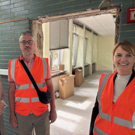 Auf dem Bild sind zwei Frauen und ein Mann in einer Schule zu sehen, die saniert wird.