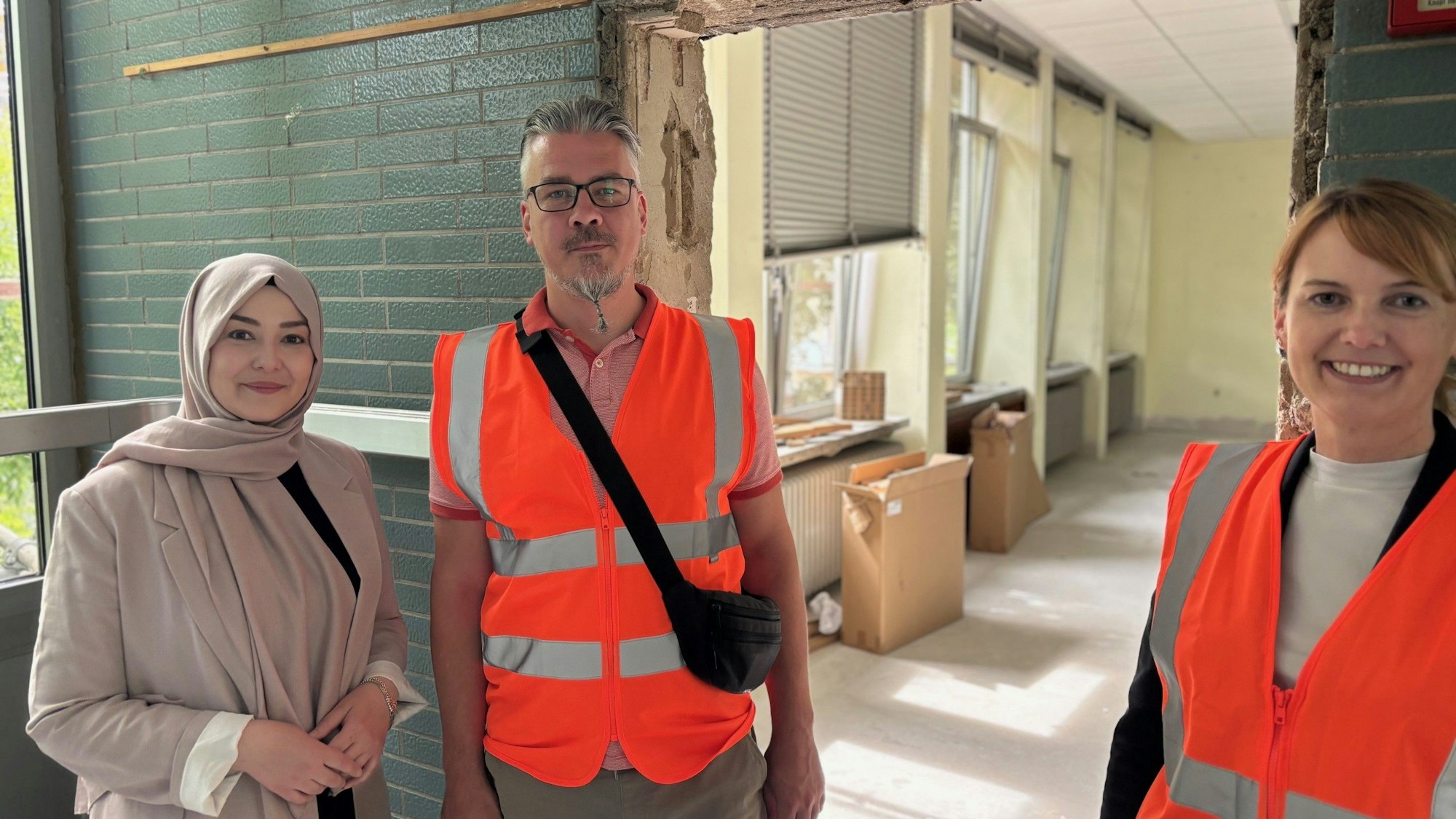 Auf dem Bild sind zwei Frauen und ein Mann in einer Schule zu sehen, die saniert wird.